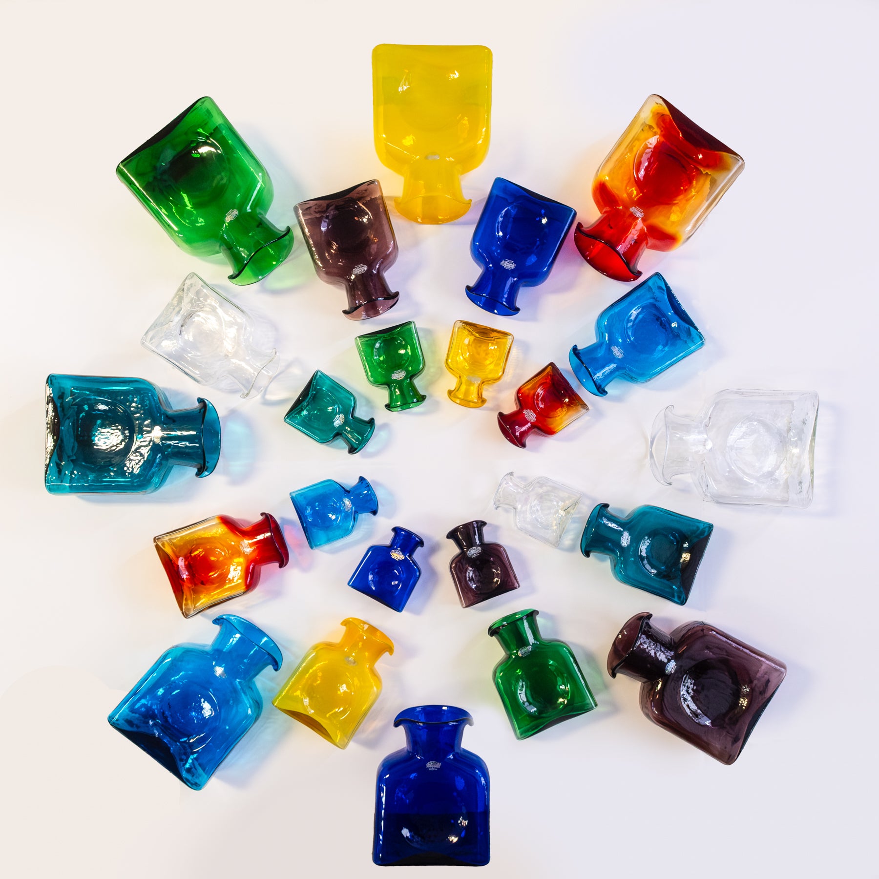 Colorful glass bottles arranged in a circular pattern on a white background