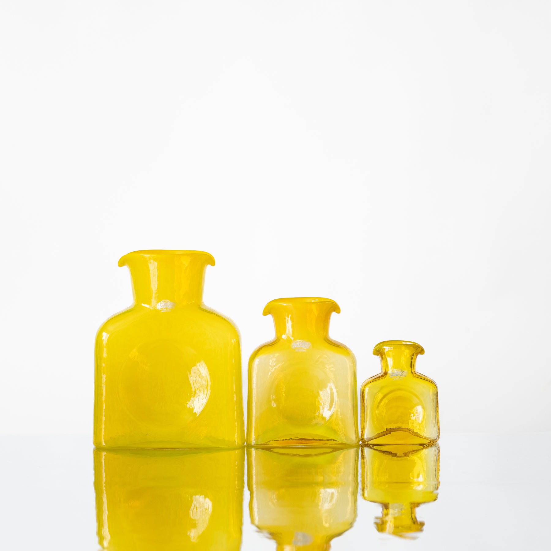 Three yellow glass bottles of varying sizes on a white background