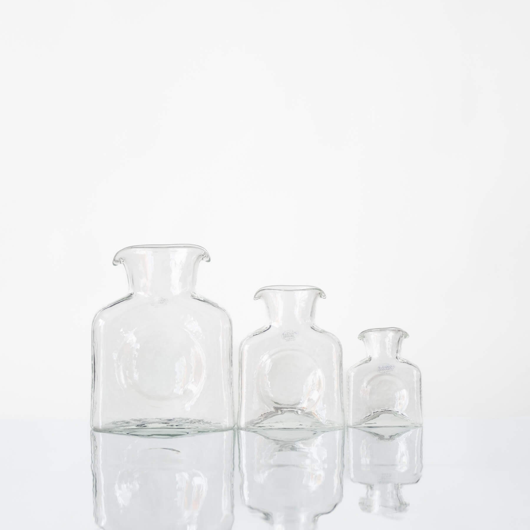 Three clear glass vases of different sizes on a white background