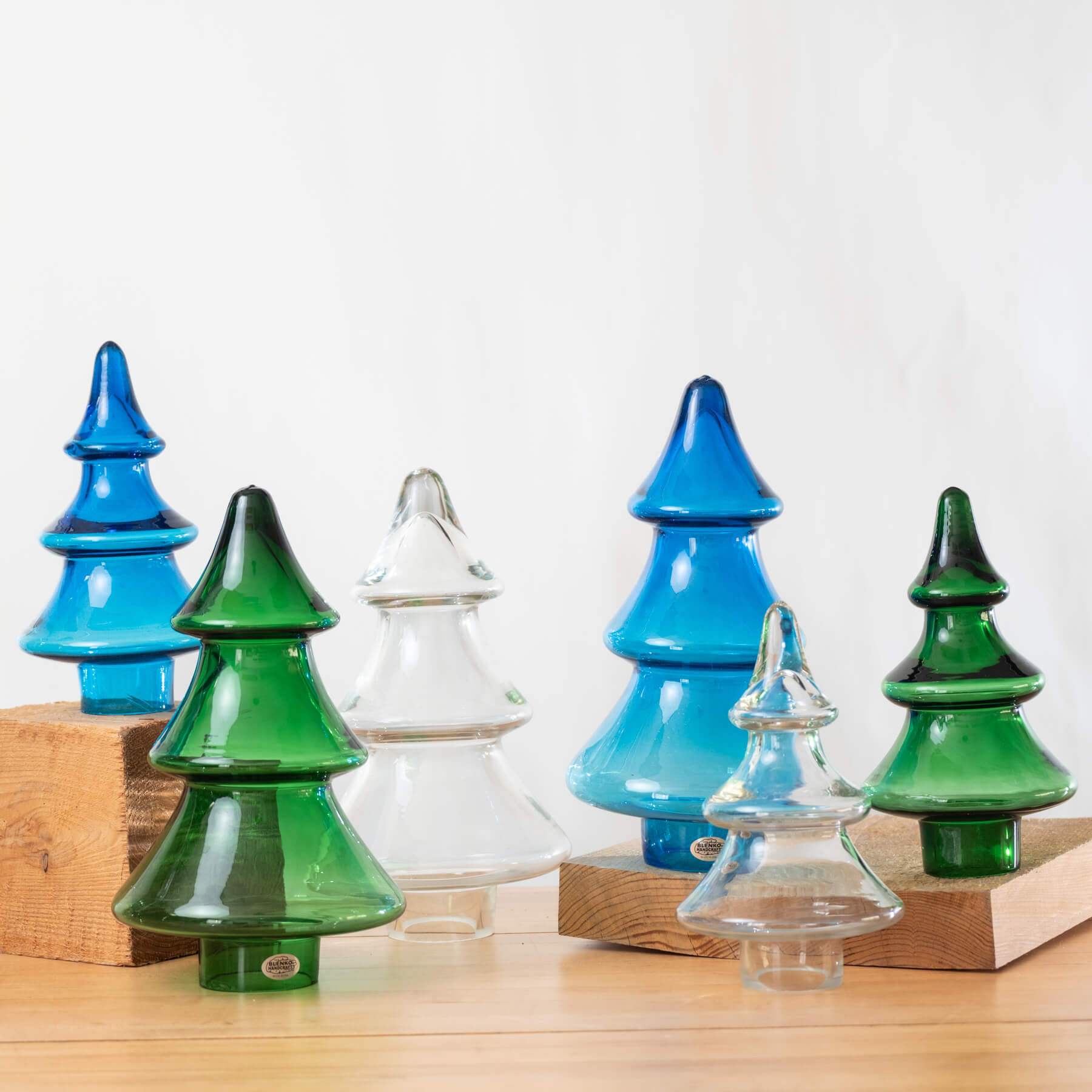 Set of colorful glass Christmas trees on a wooden surface with a white background