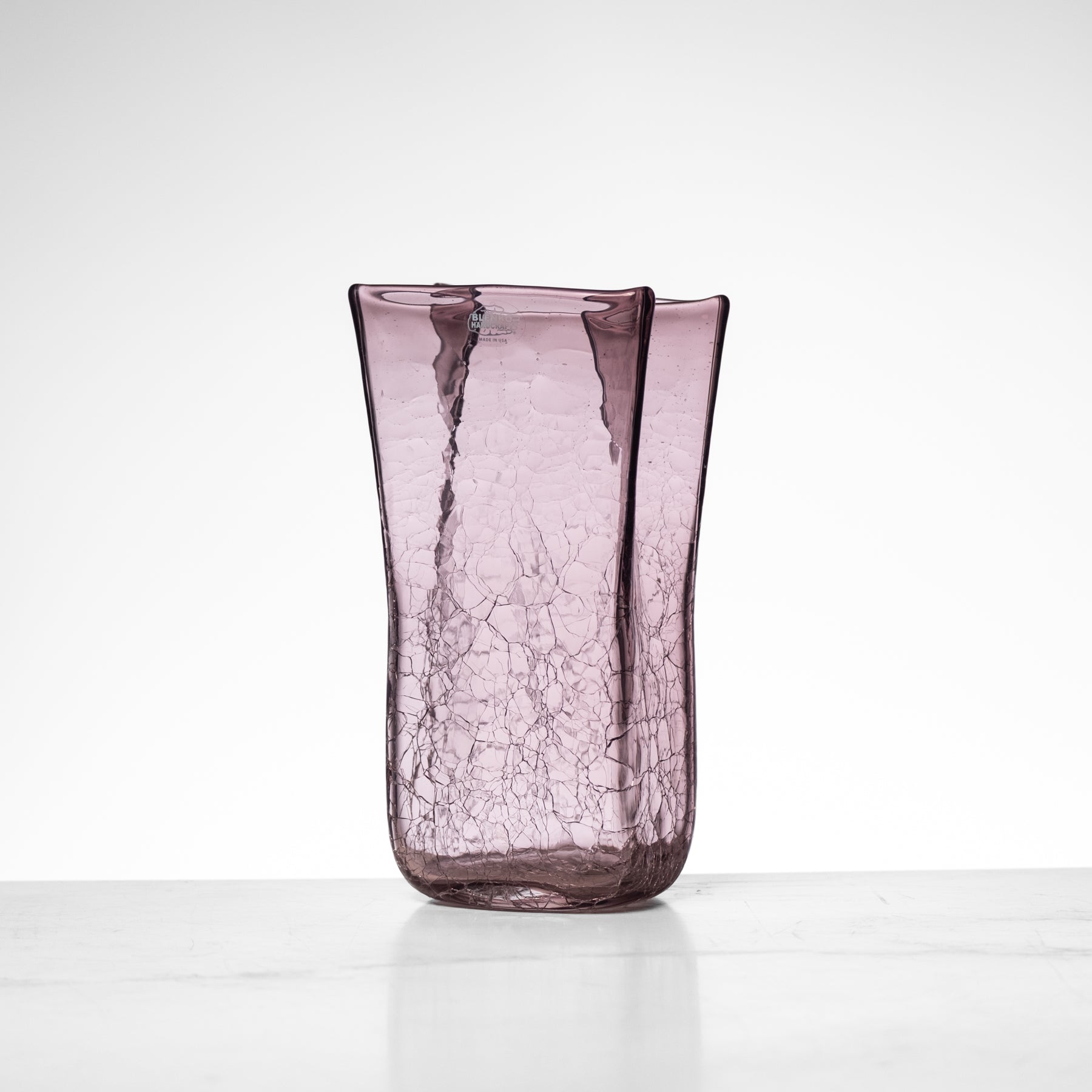 Purple glass vase with a cracked texture on a white background