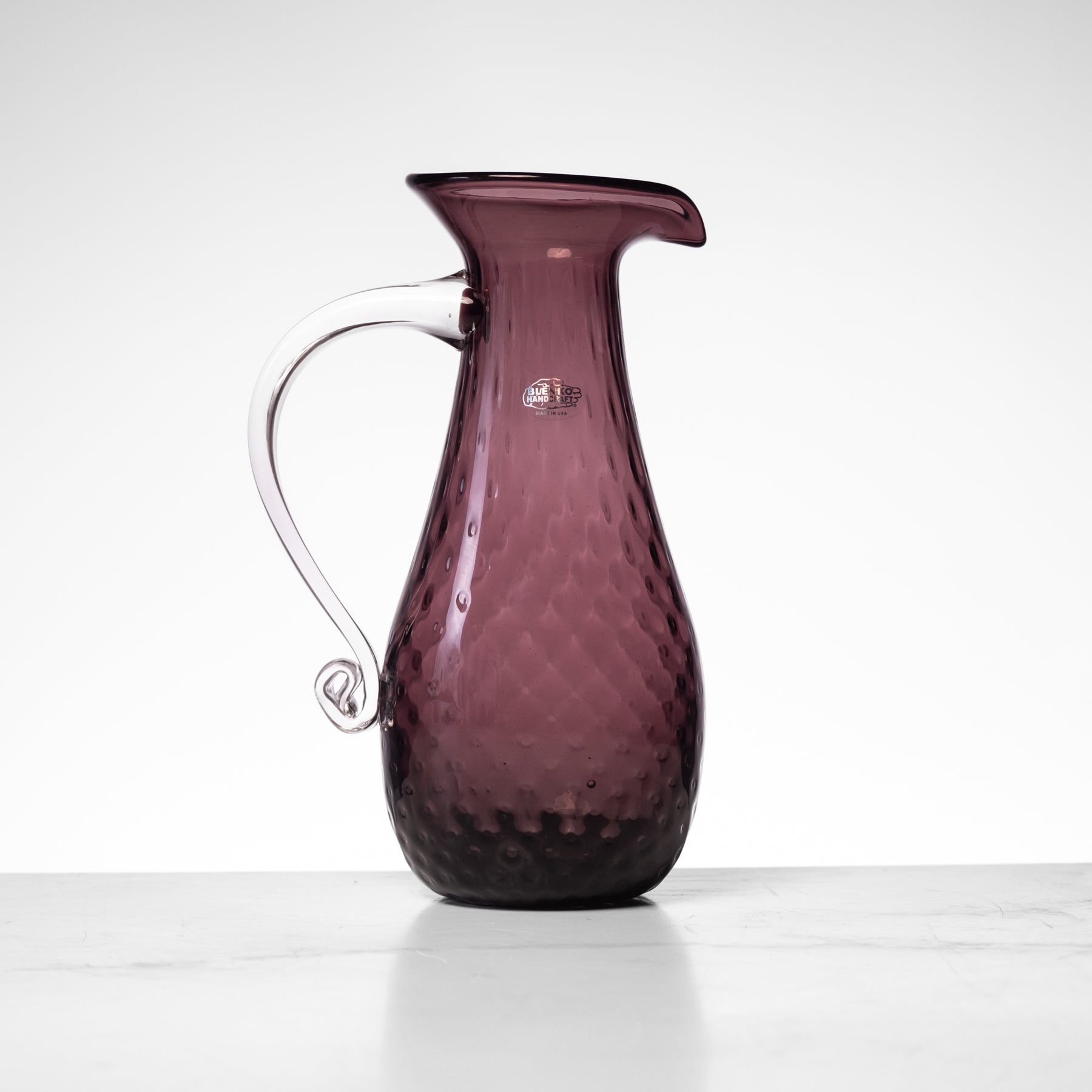 Amethyst glass carafe on a white background