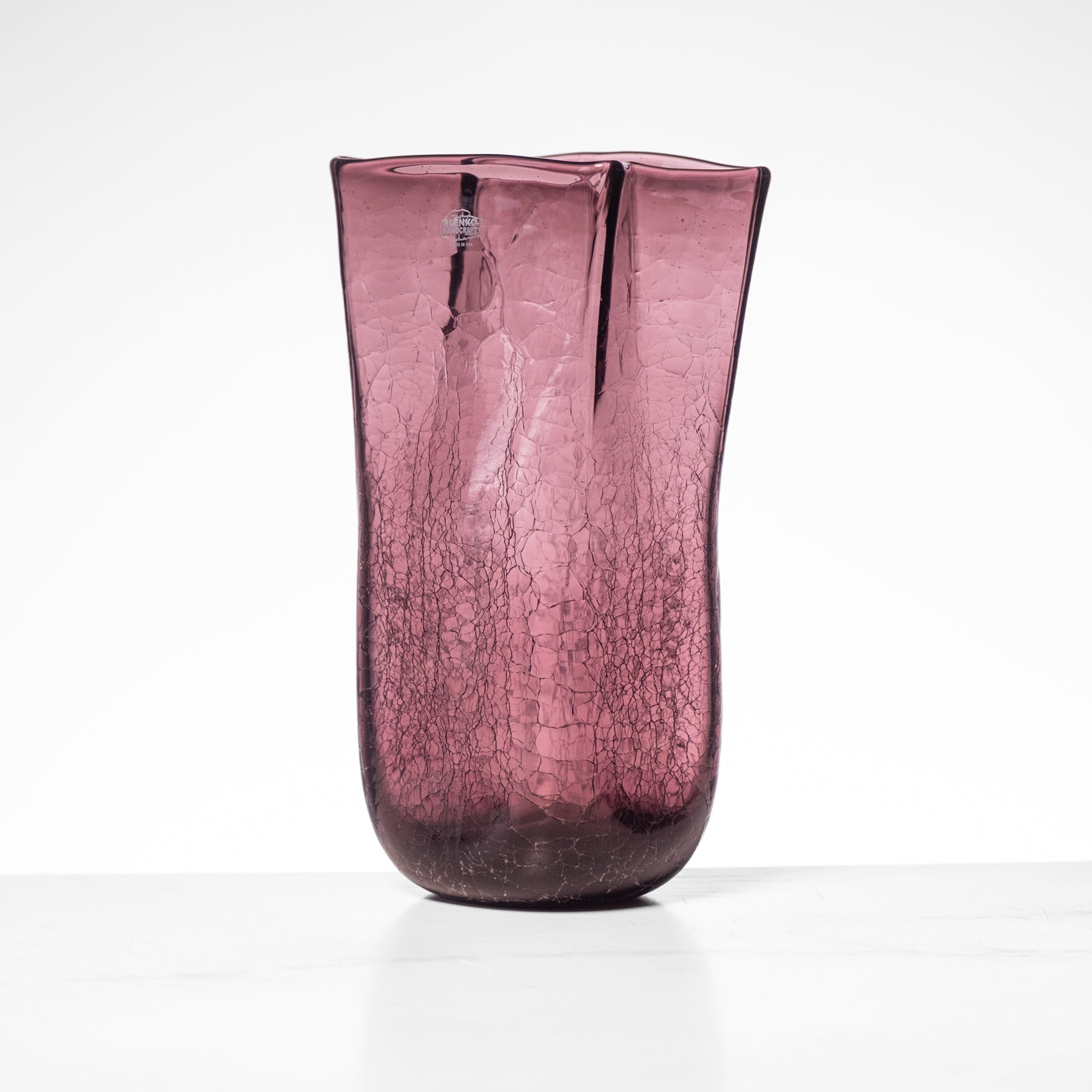 Purple cracked glass vase on a white background