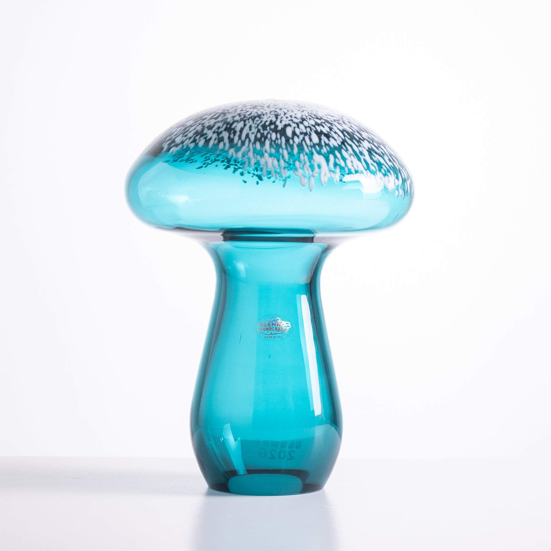 Turquoise glass mushroom sculpture on a white background