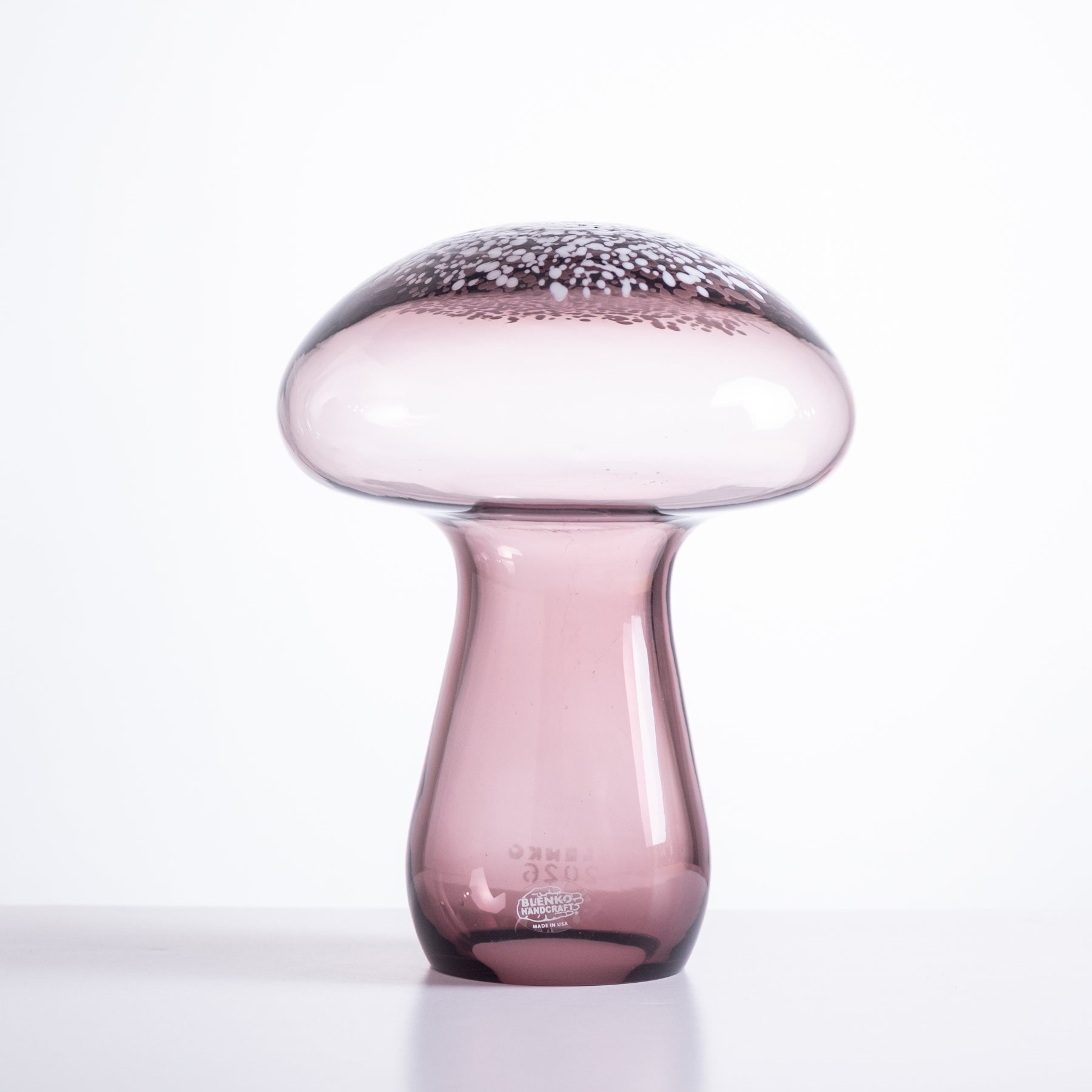 Pink glass vase with textured top on a white background