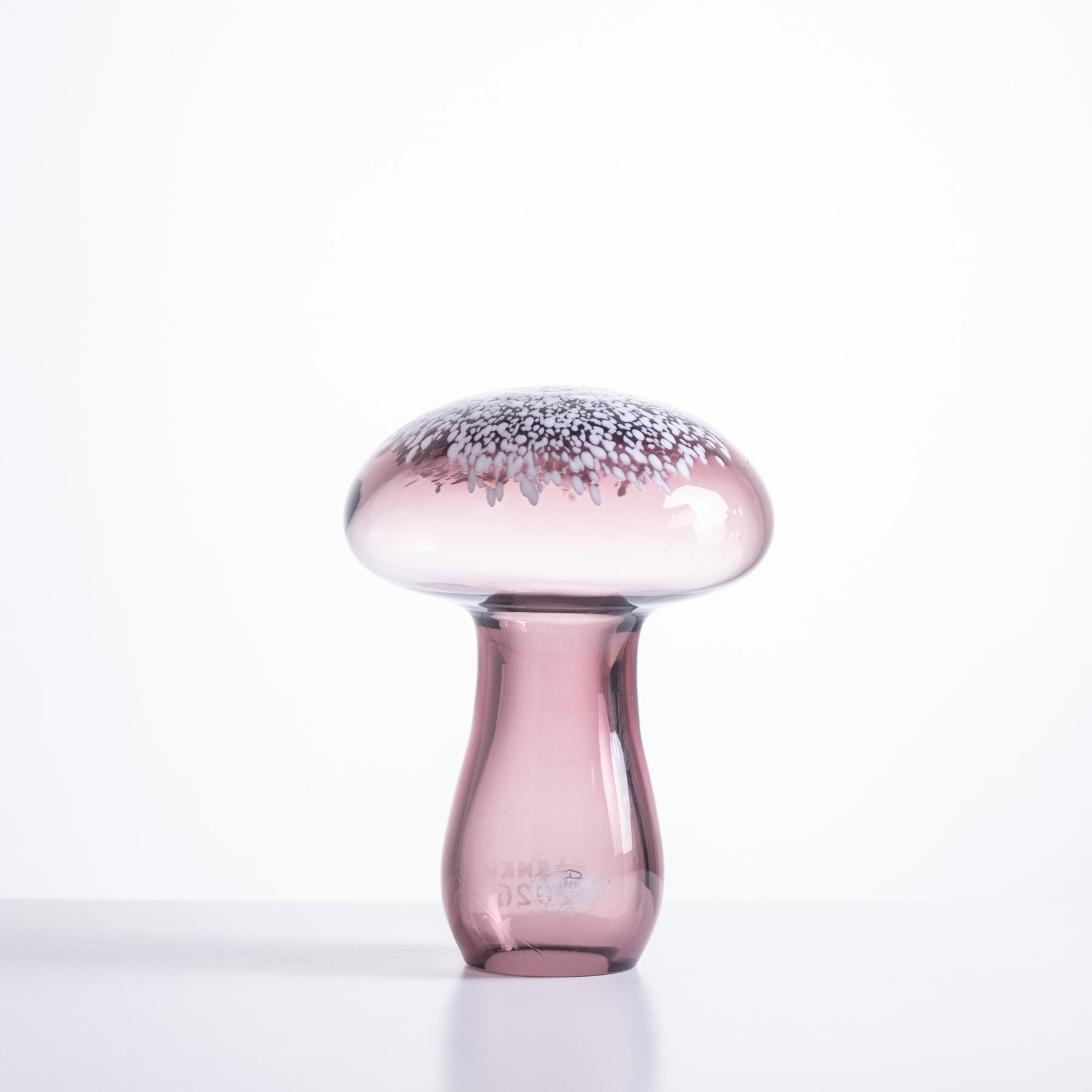 Pink glass mushroom-shaped object on a white background