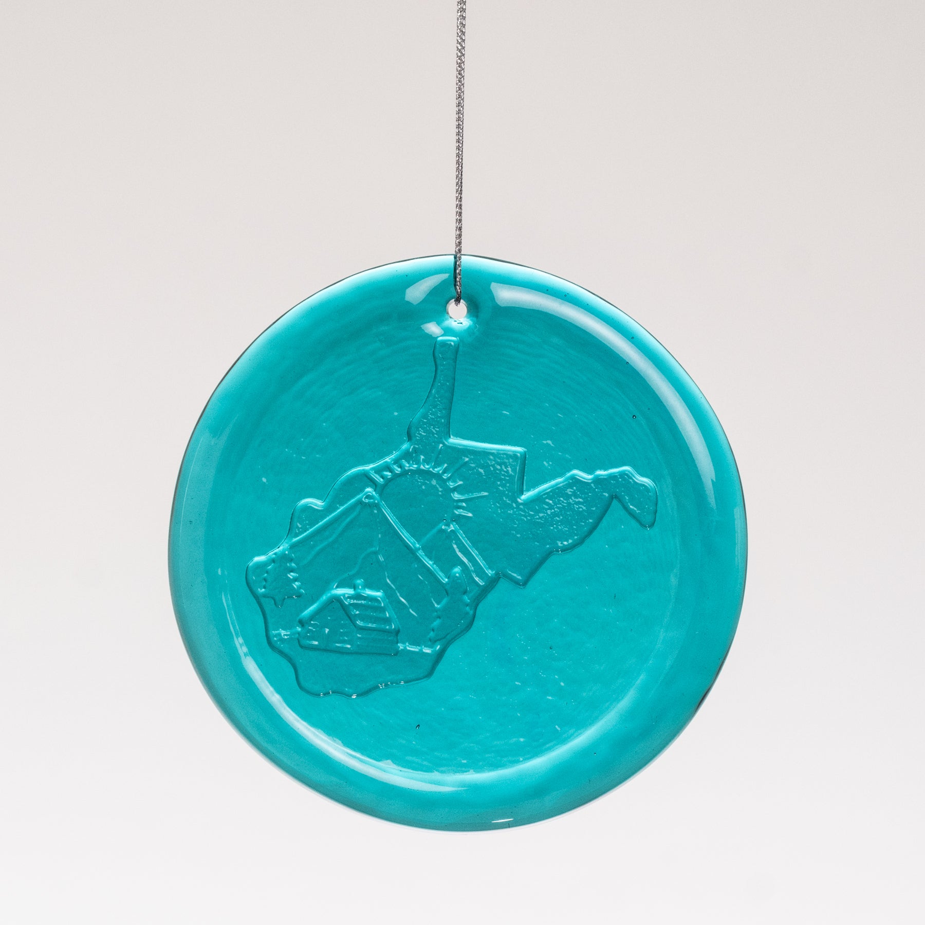 Turquoise ceramic ornament with embossed design on a white background