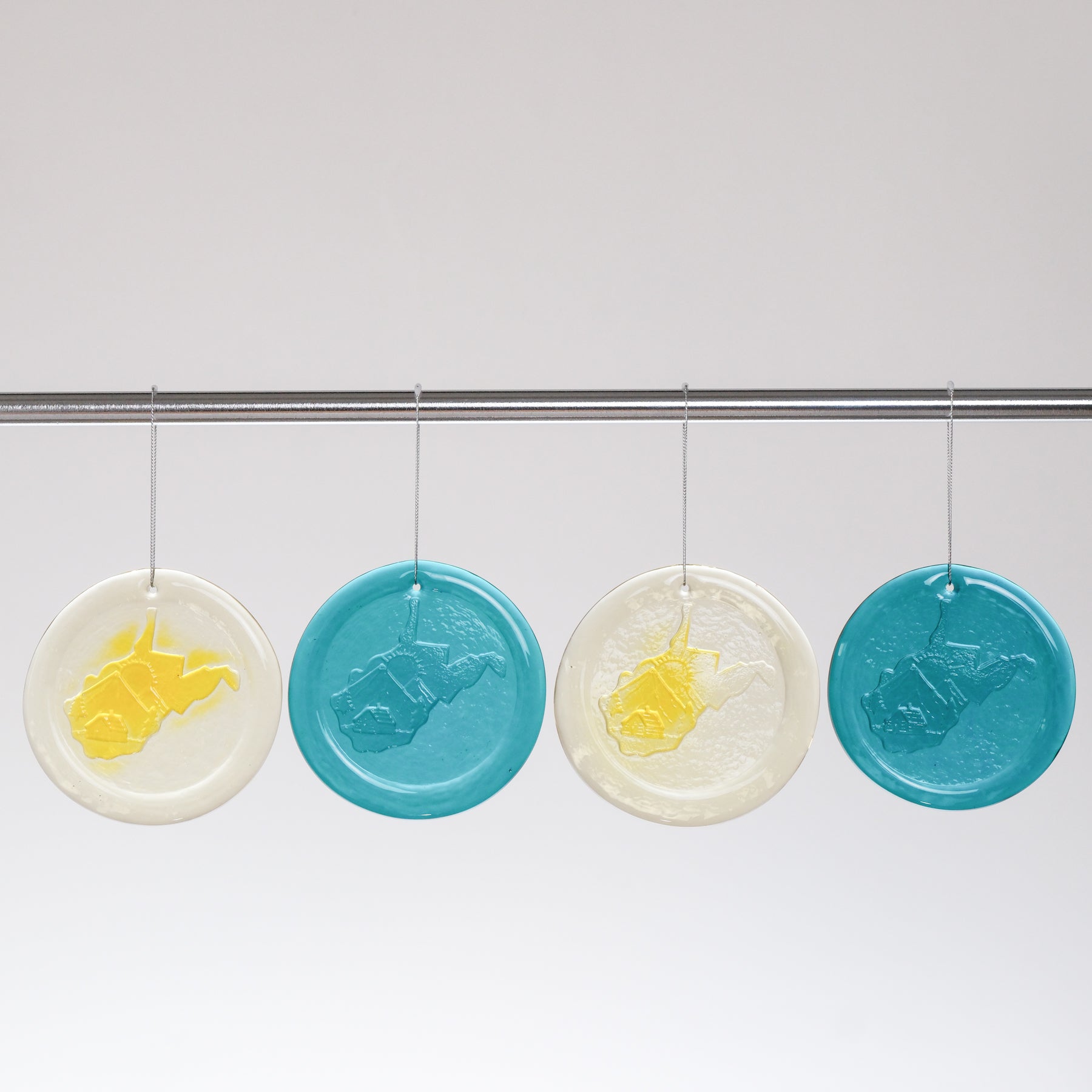 Four circular blue and white soap bars hanging on a rod against a white background