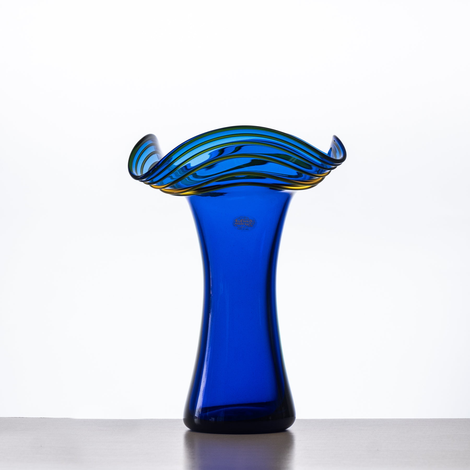 Blue glass vase with wavy rim on a white background
