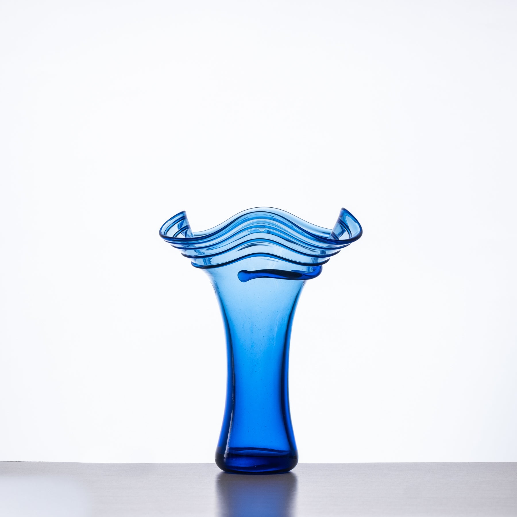 Blue glass vase with wavy design on a white background