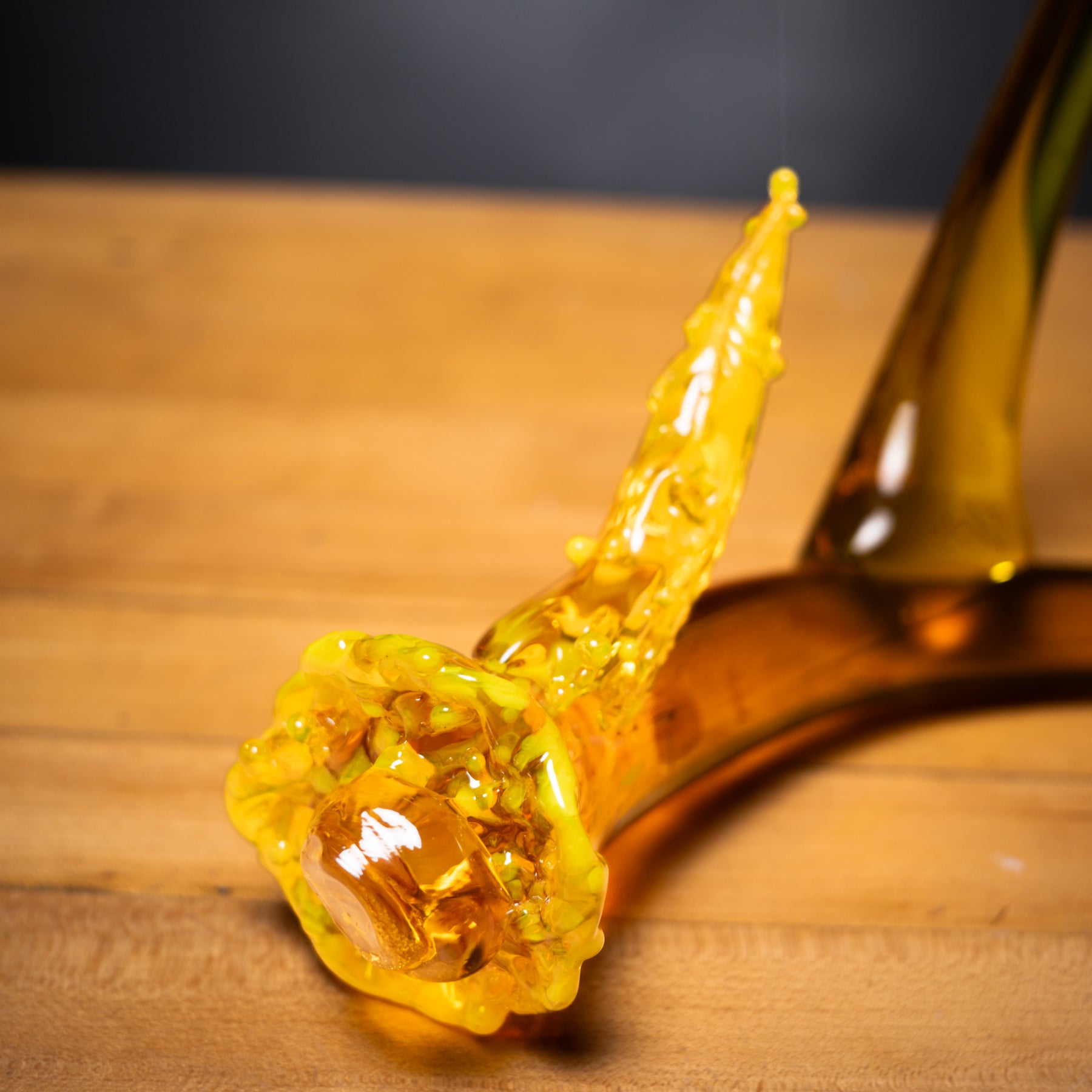 Glass pipe with yellowish-brown liquid on a wooden surface