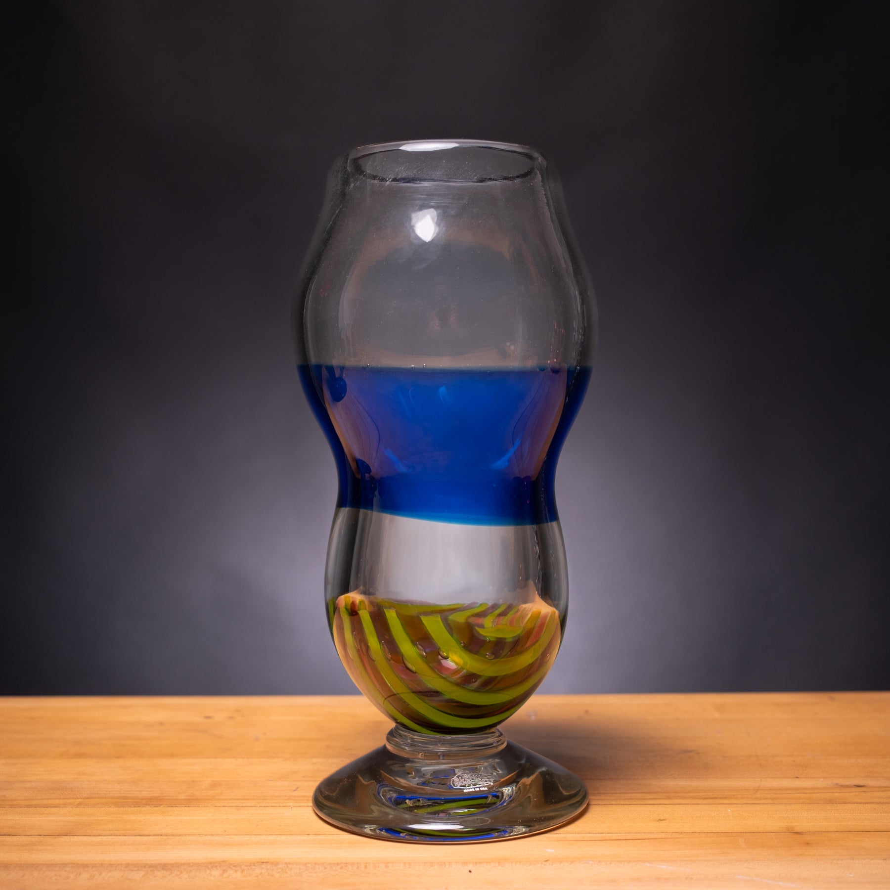 Glass with blue and green liquid on a wooden surface and dark background