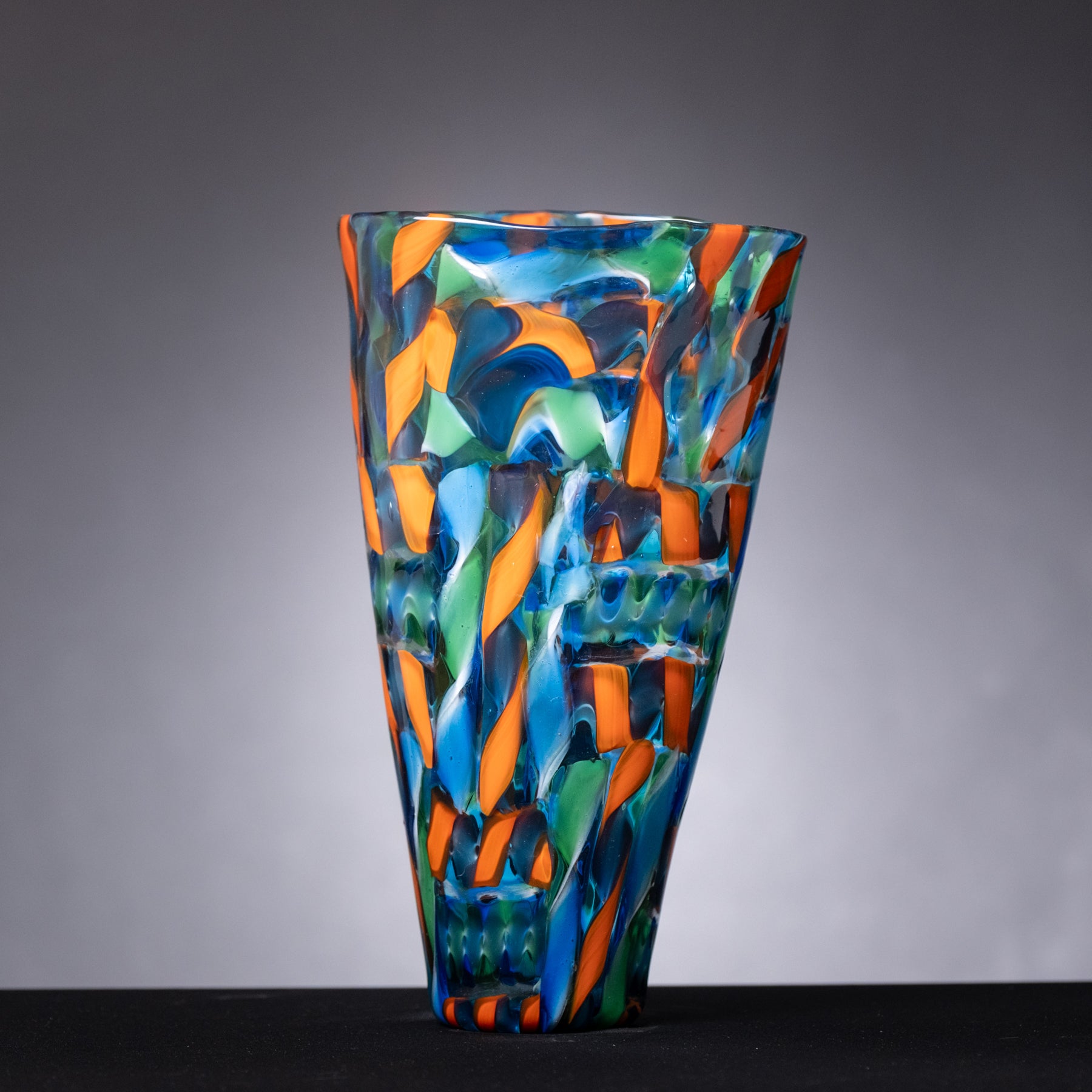 Colorful glass vase with abstract design on a gray background
