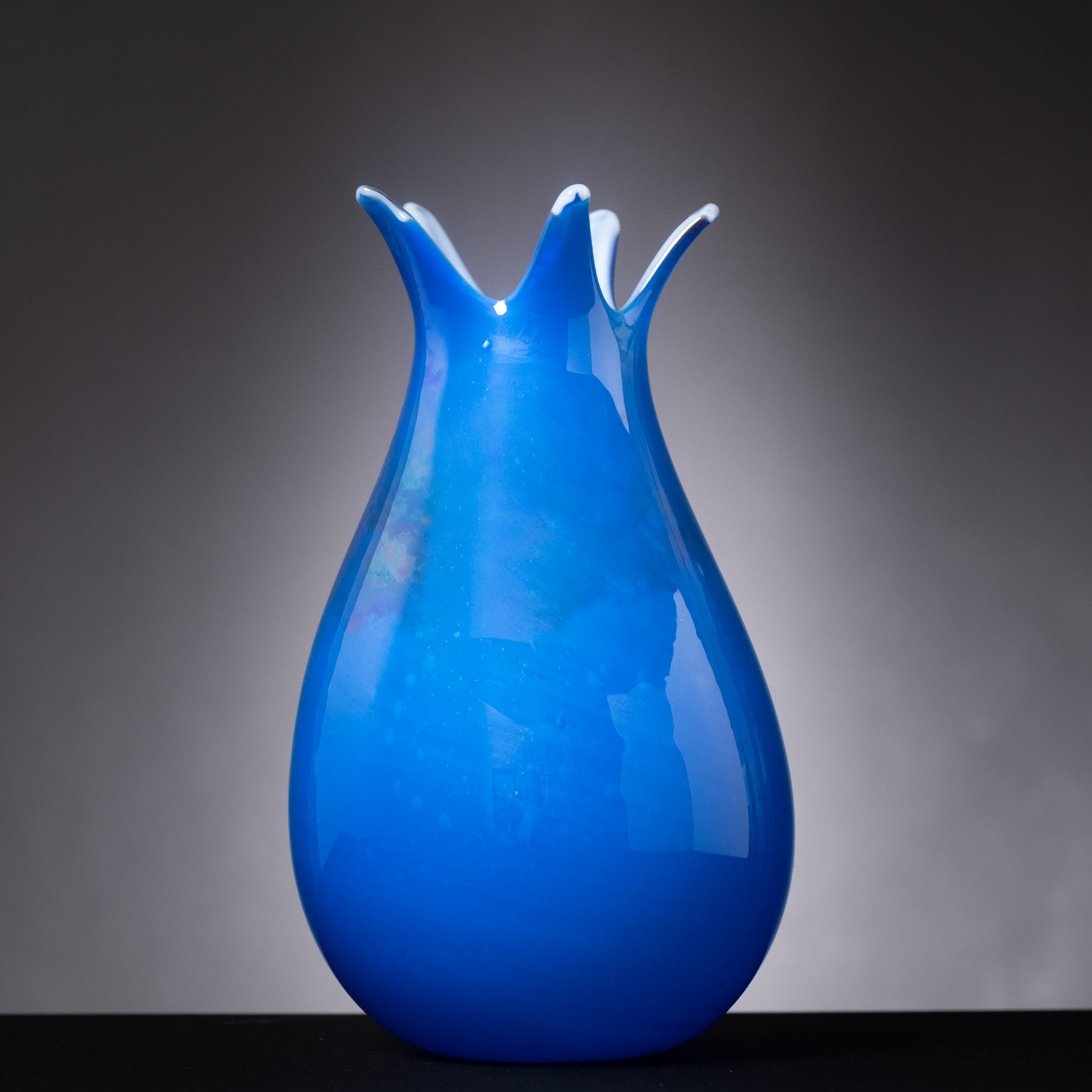 Blue glass vase with a unique design on a dark background