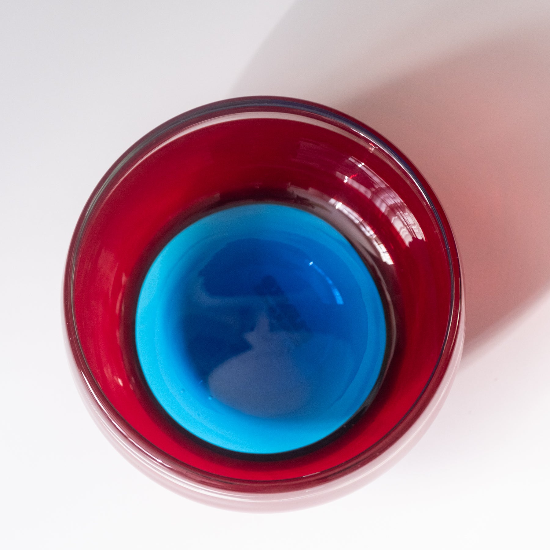 Red glass container with a blue interior on a white background