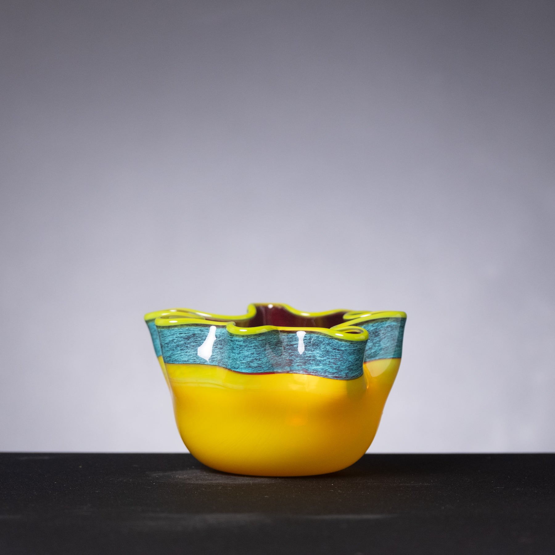 Yellow glass bowl with blue interior on a gray background