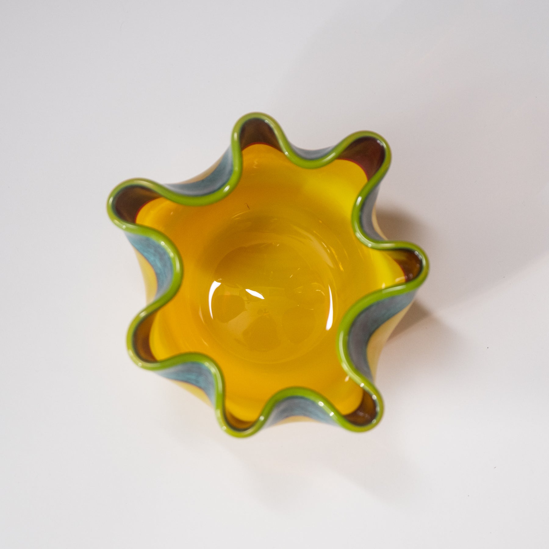 Yellow glass bowl with wavy edge on a white background