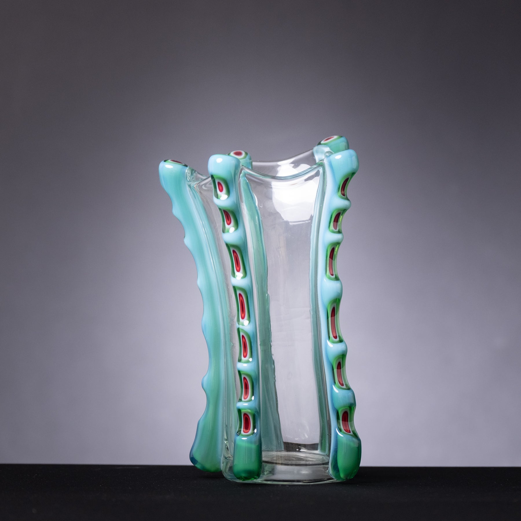 Glass vase with green textured exterior and clear interior on a gray background