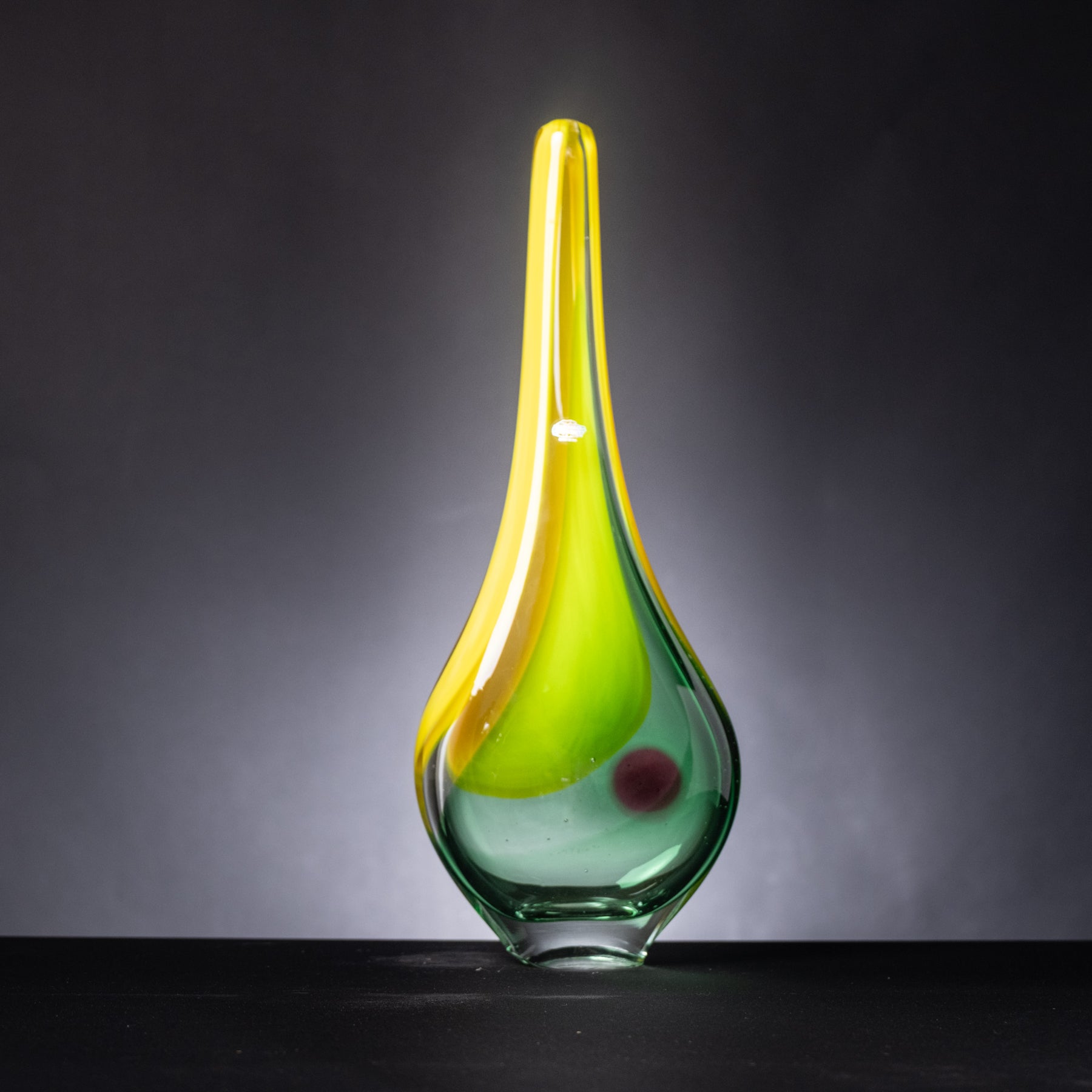 Glass vase with yellow and green gradient on a dark background