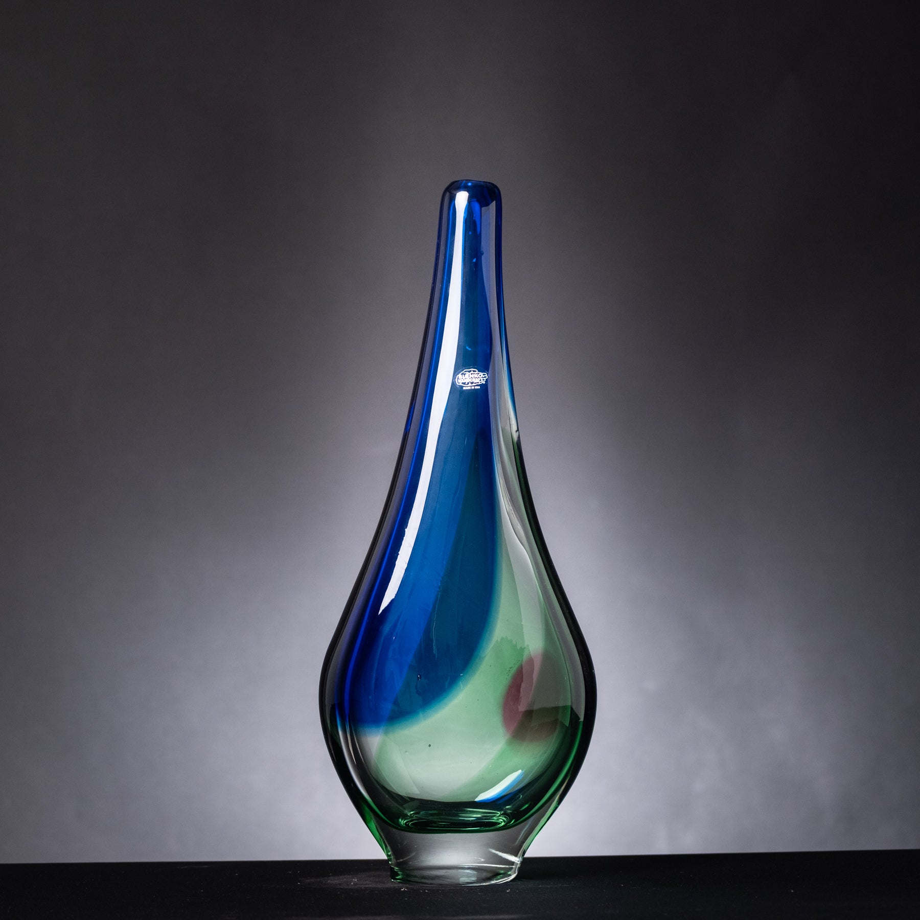 Glass vase with blue and green gradient on a dark background