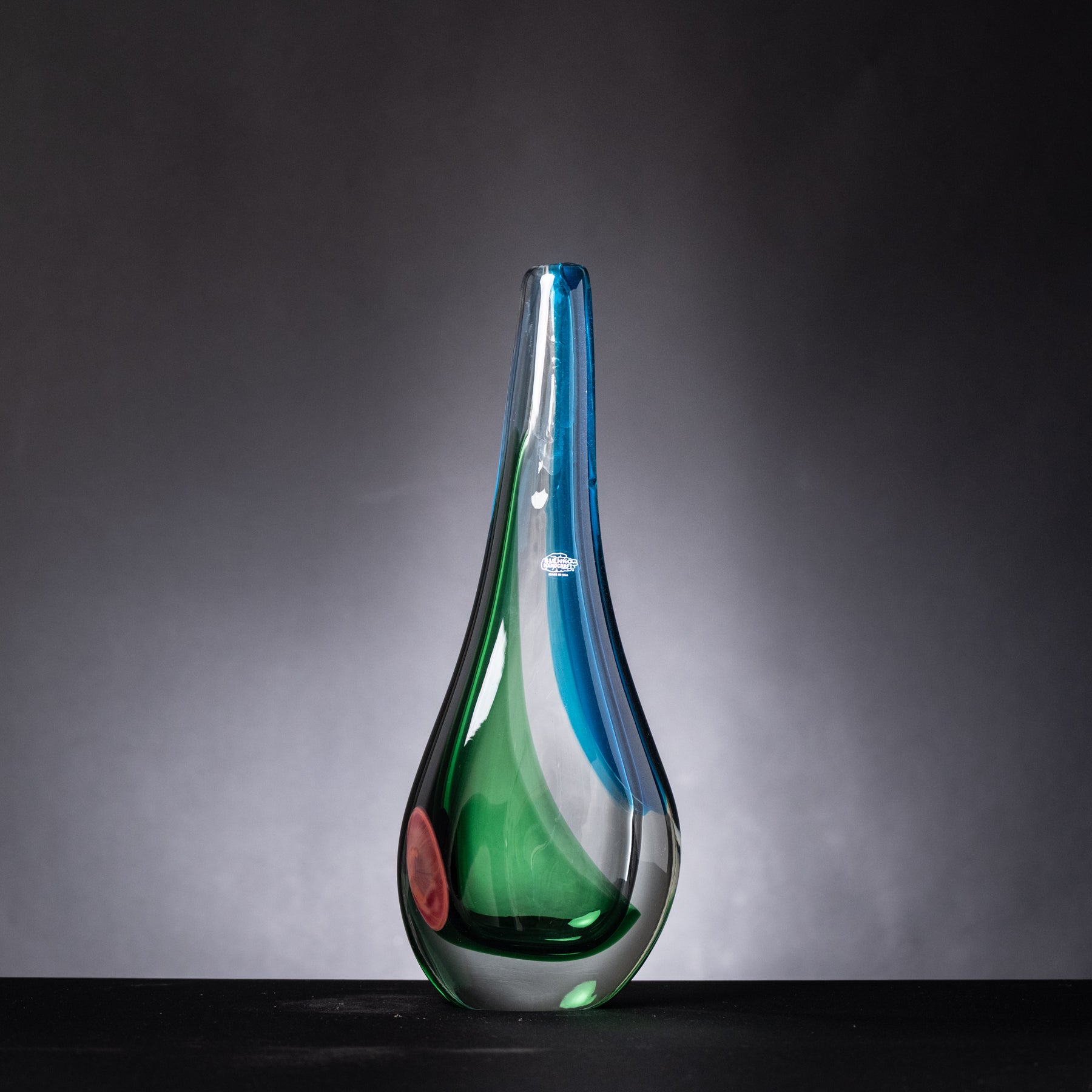 Glass vase with blue and green gradient on a dark background
