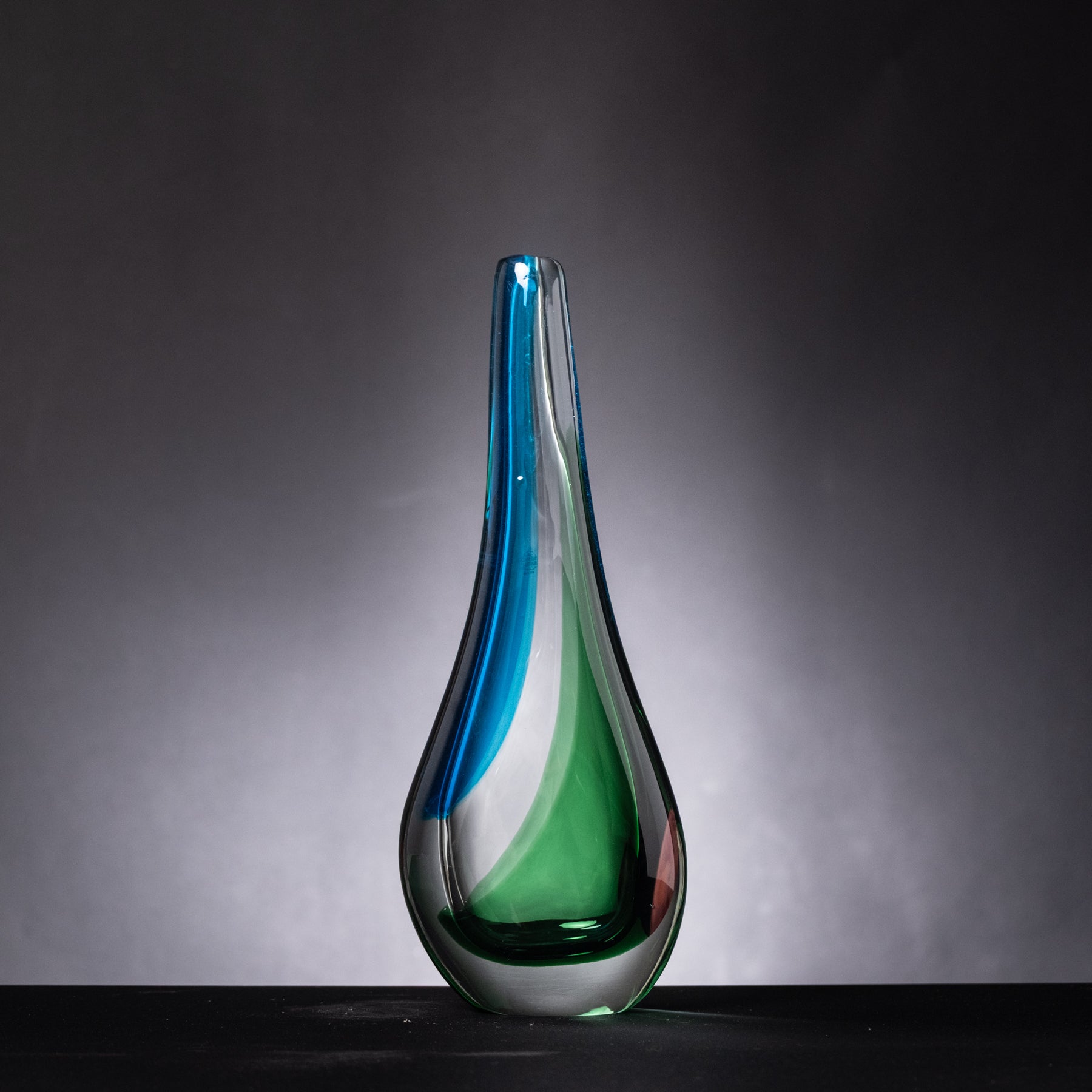 Glass vase with blue and green gradient on a dark background