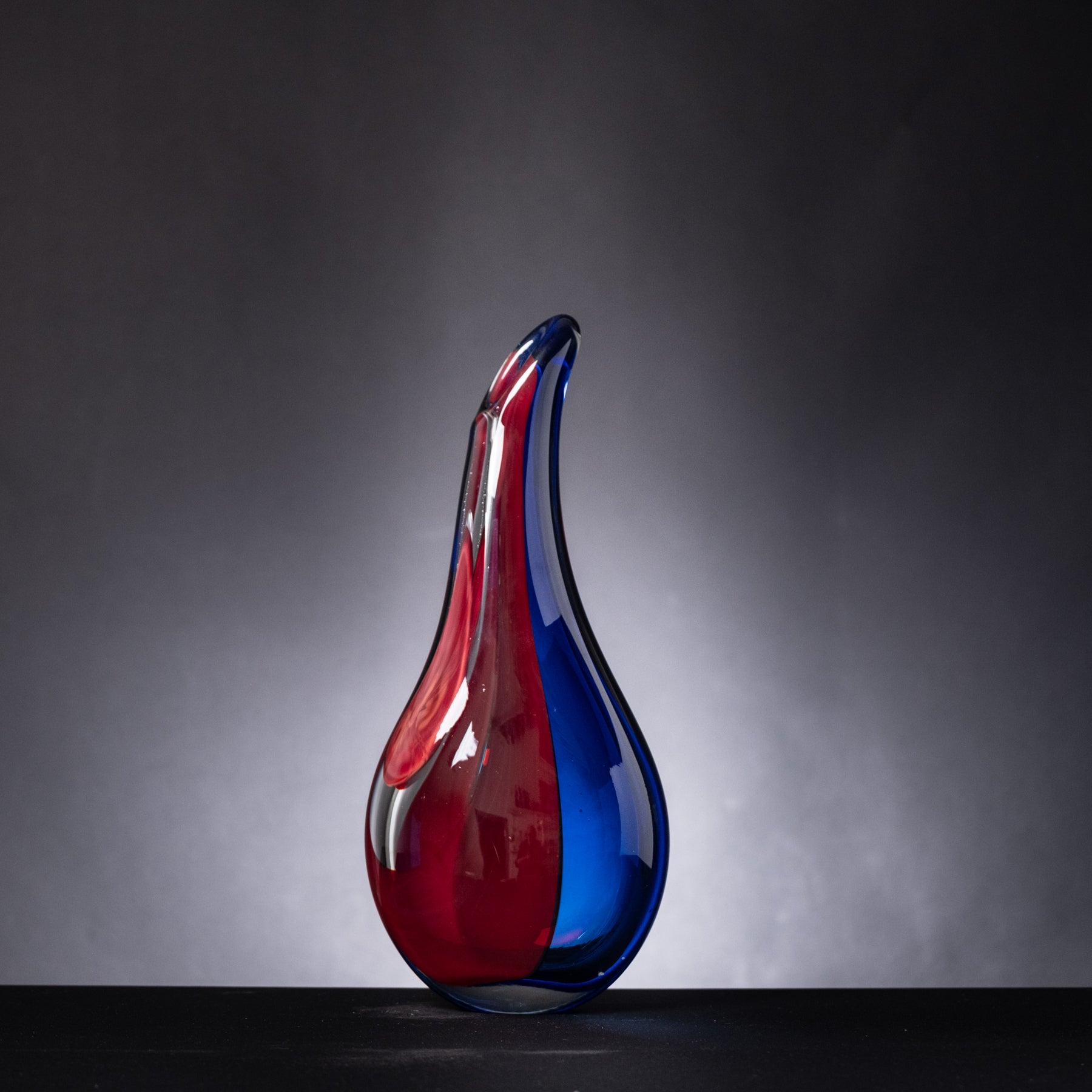 Glass vase with red and blue gradient on a dark background