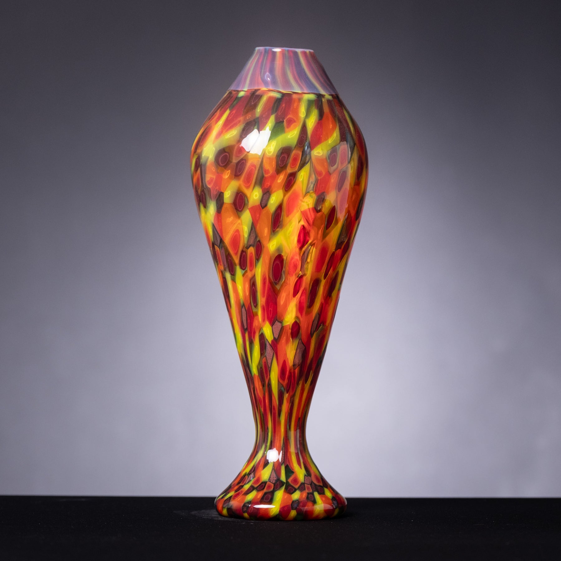 Colorful glass vase with a flame-like pattern on a gray background