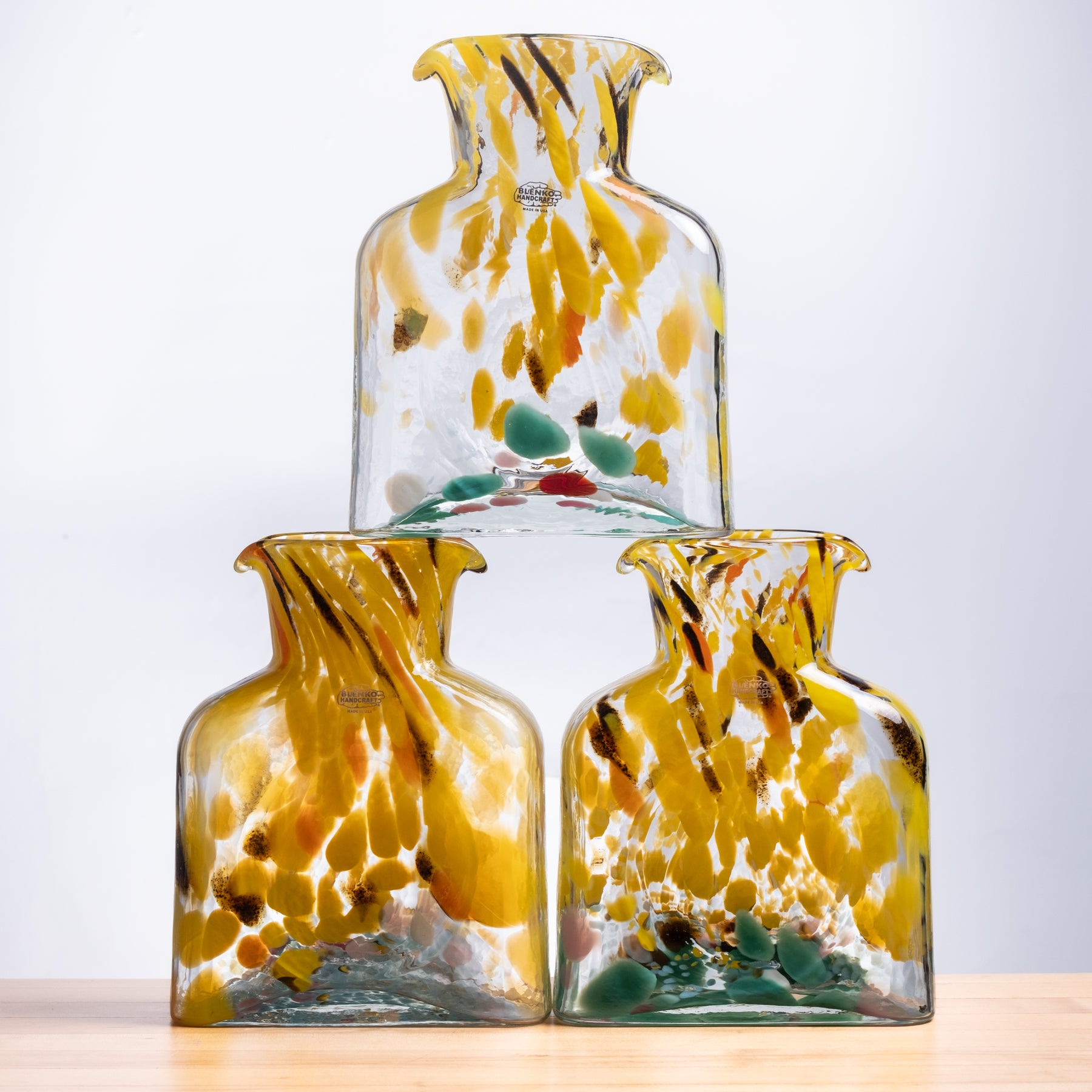 Three glass vases with yellow and brown abstract patterns on a light background