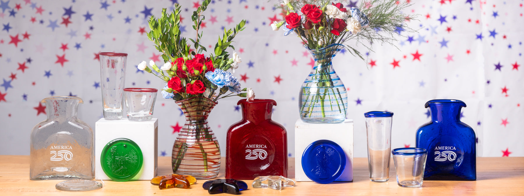 Collection of American 250 glassware with decorative flowers and a colorful star-patterned wall.