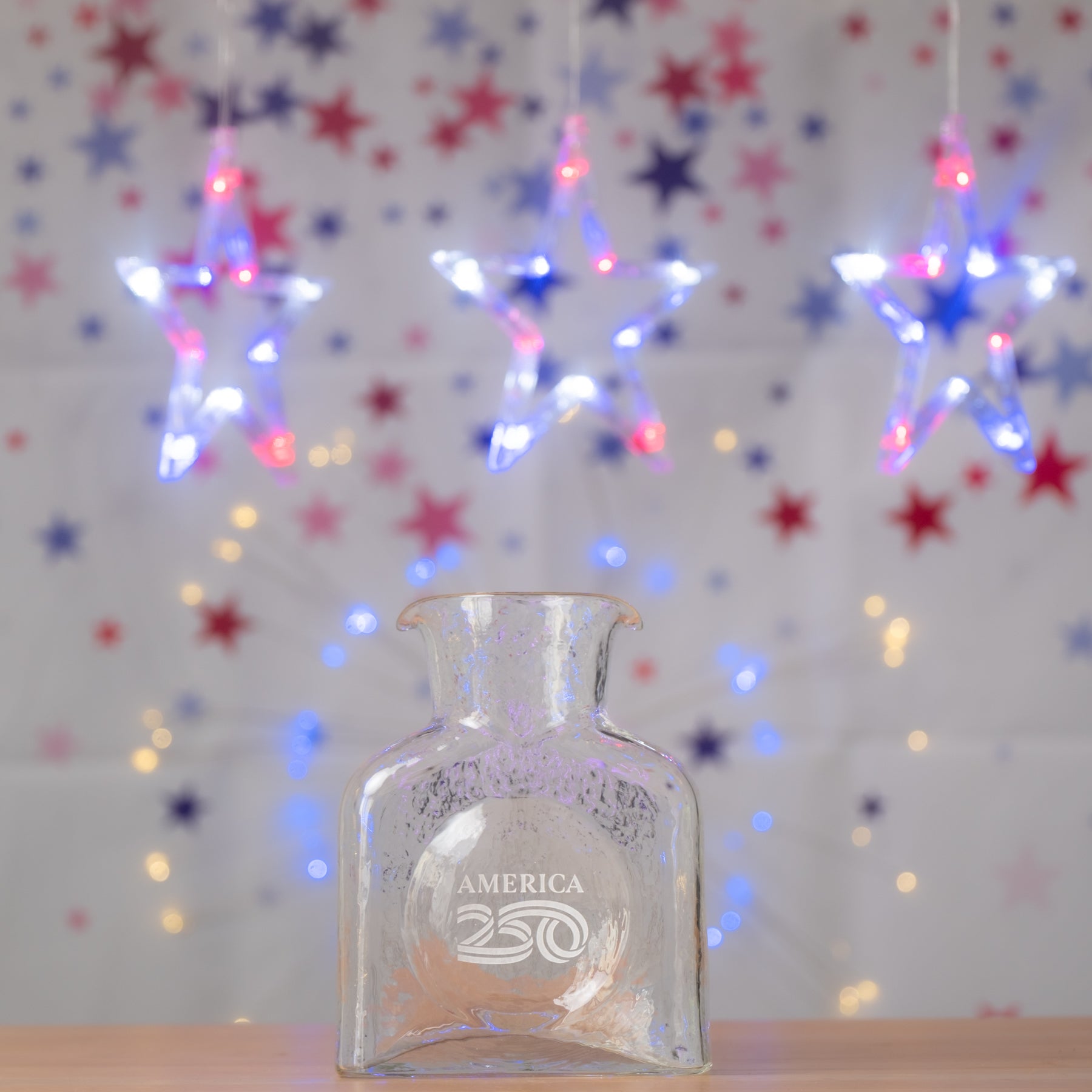 Clear glass bottle with 'America' engraving on a star-patterned background with lights