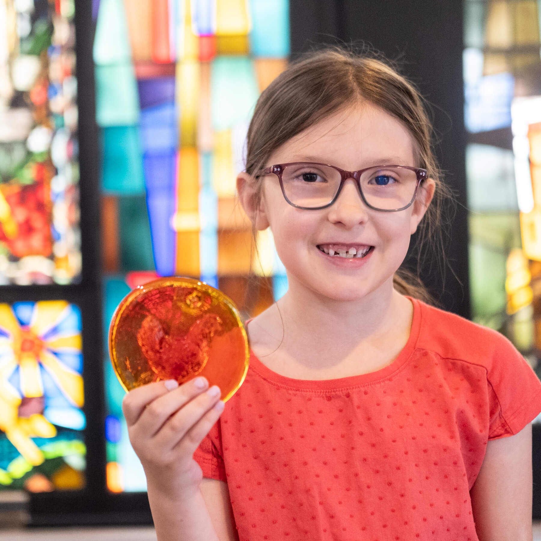 girl with a tangerine sun-catcher with a chicken on it