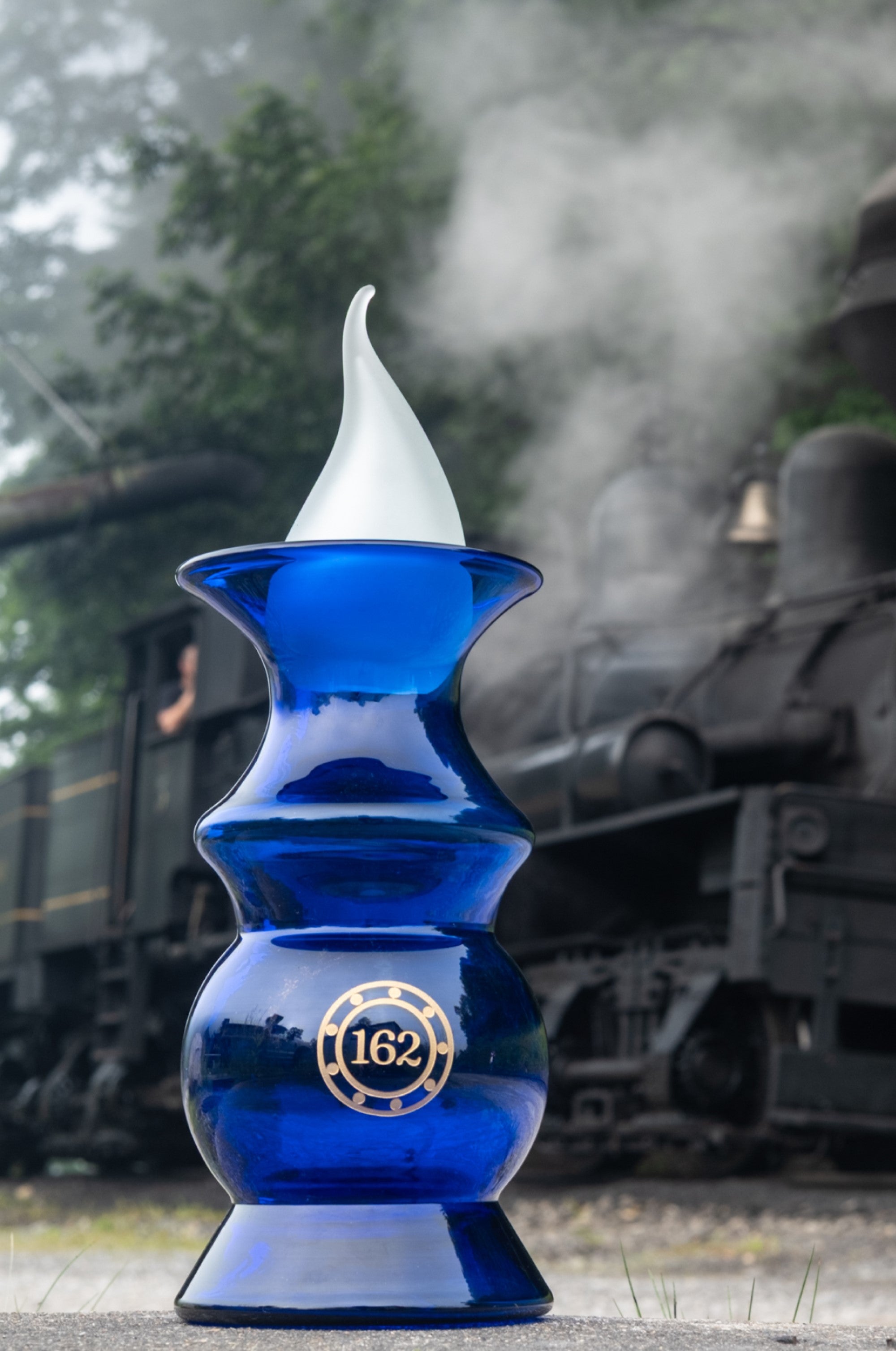 Blue vase with white top in front of a steam locomotive
