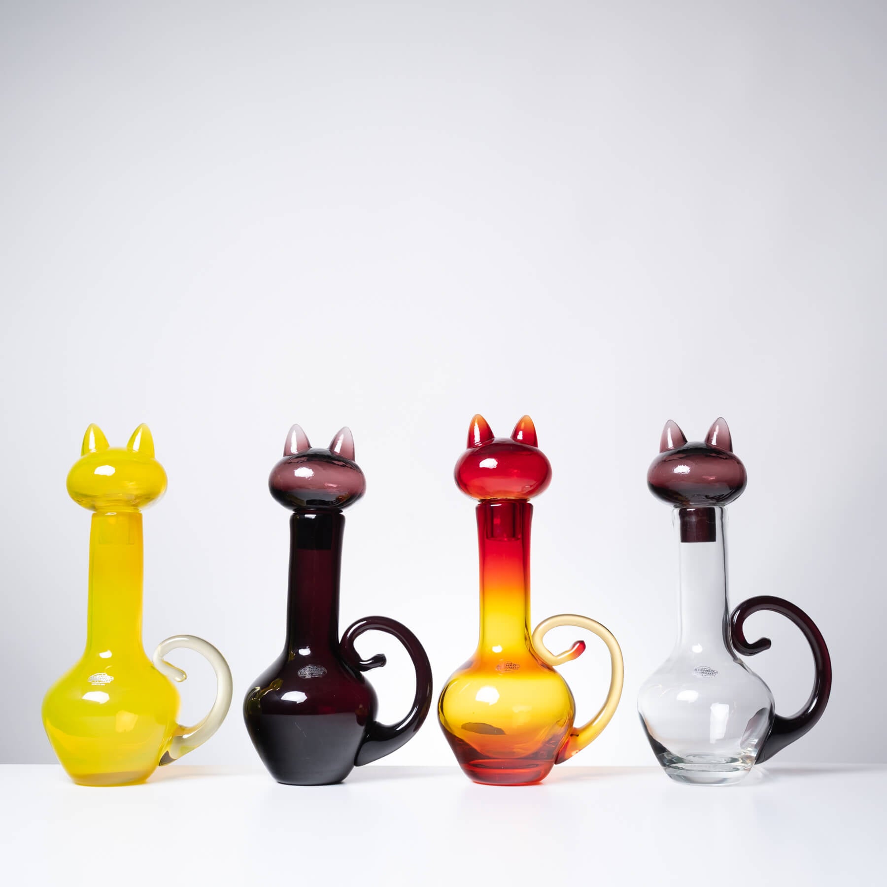 Four colorful cat shaped bottles against a white background
