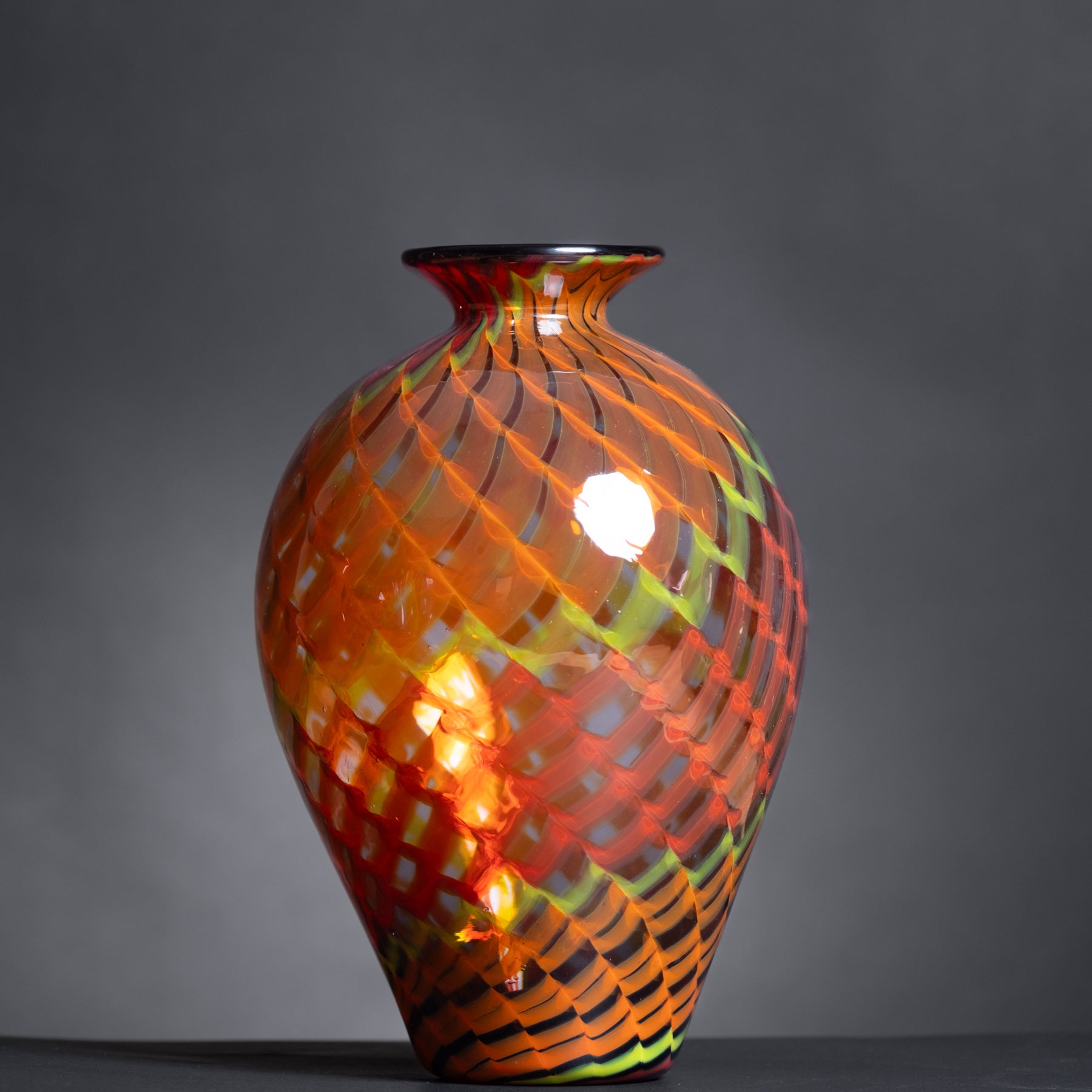 Colorful glass vase with a textured pattern on a dark background