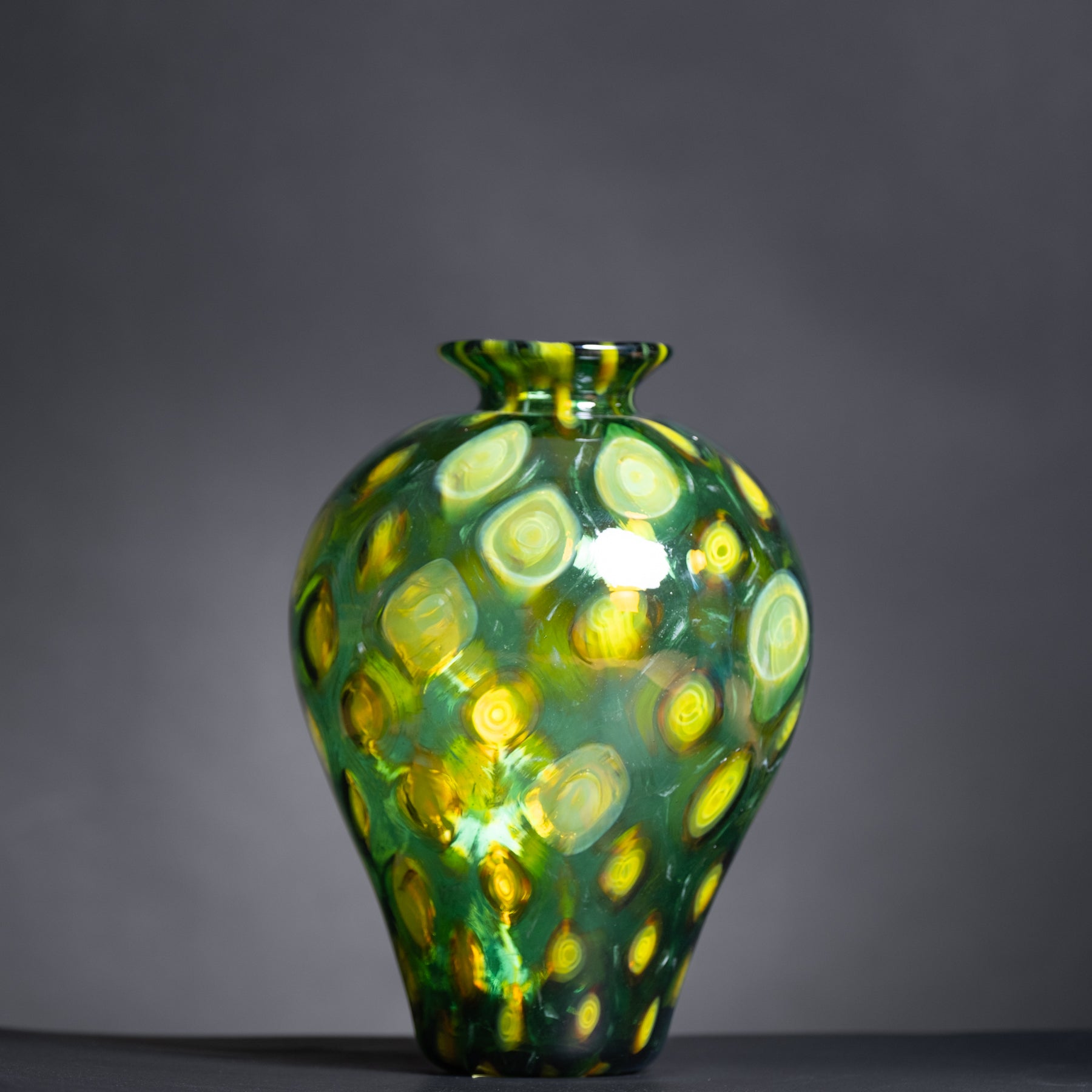 Green and yellow patterned vase on a dark background