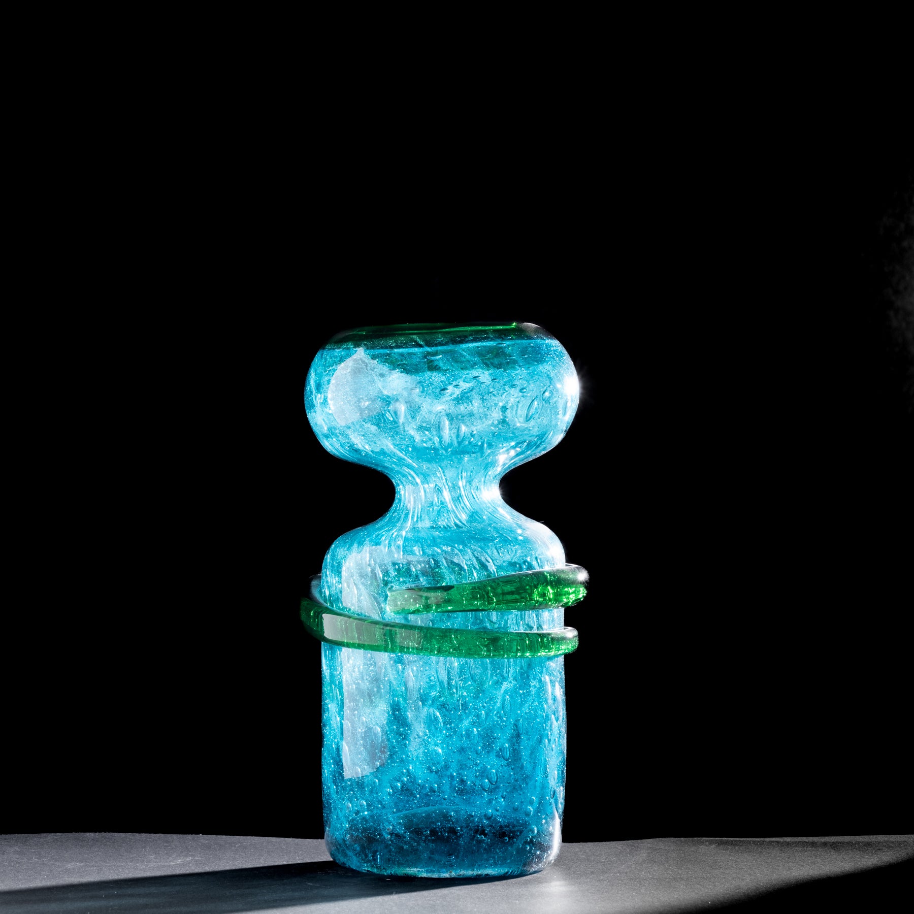 Blue and green glass sculpture on a black background