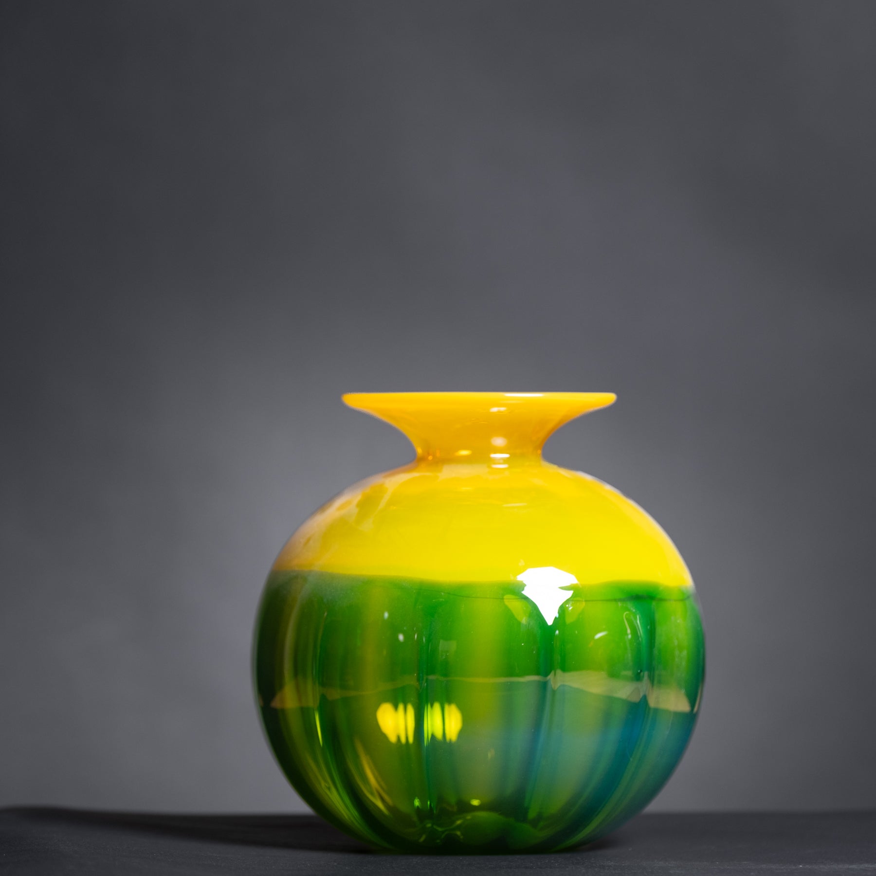 Yellow and green glass vase on a dark background
