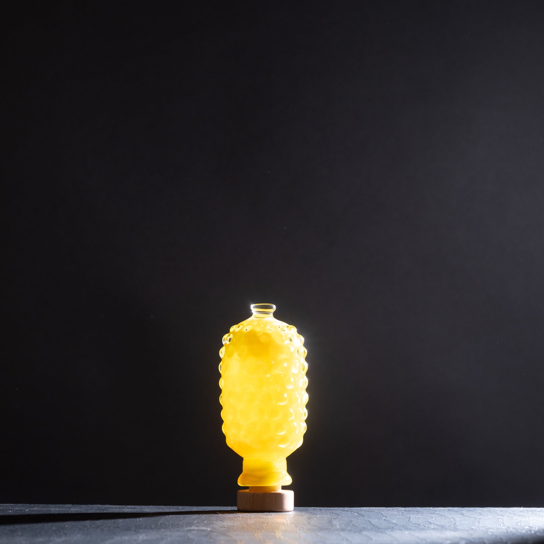 Yellow glass bottle with textured surface on a dark background