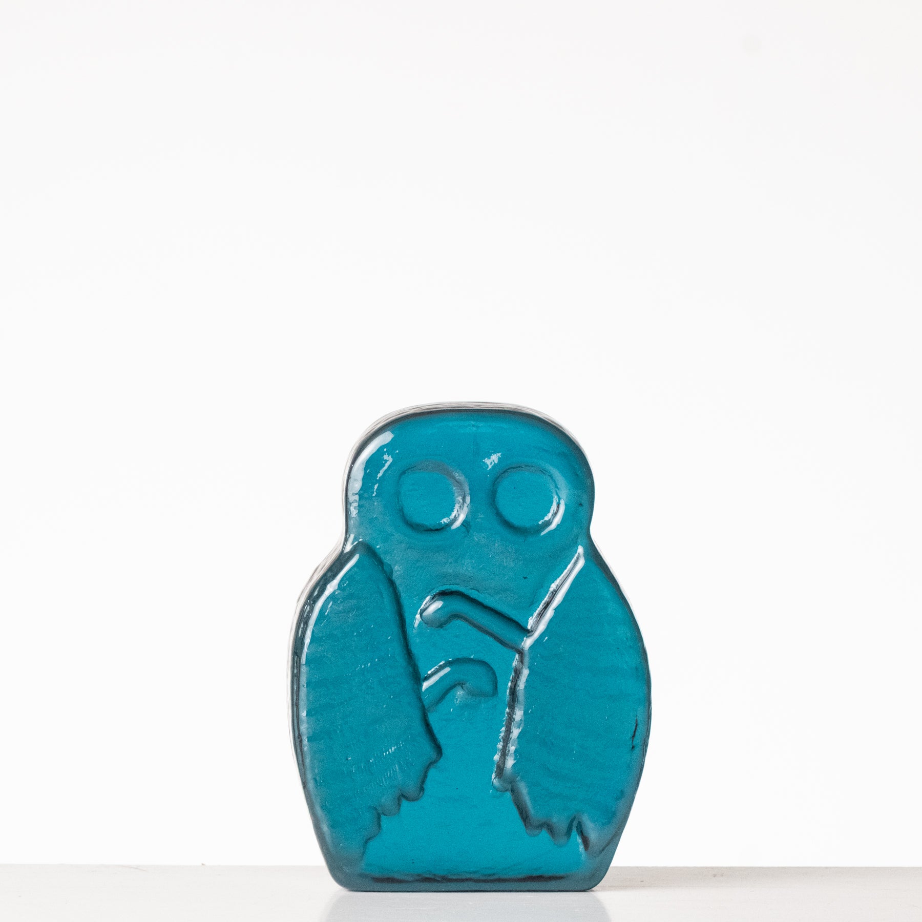 Teal owl-shaped object on a white background