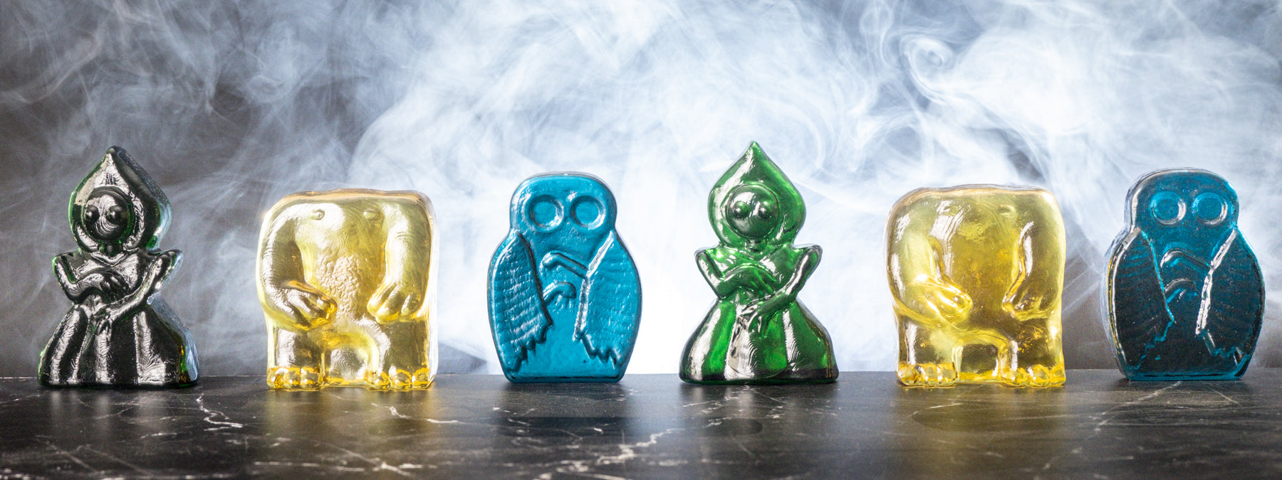Set of colorful glass figurines on a dark surface with a blurred light gray background