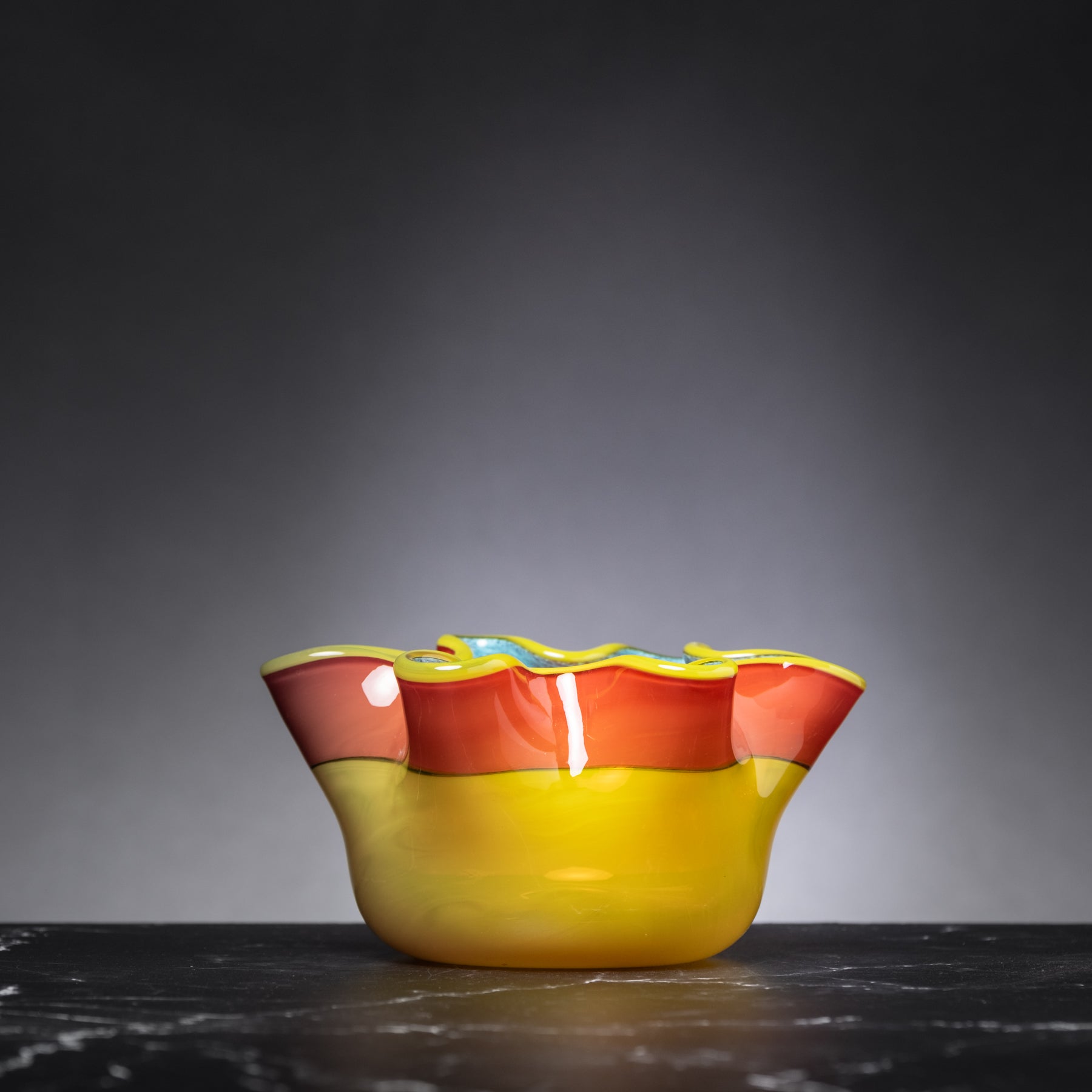 Colorful glass bowl on a dark surface with a gray background