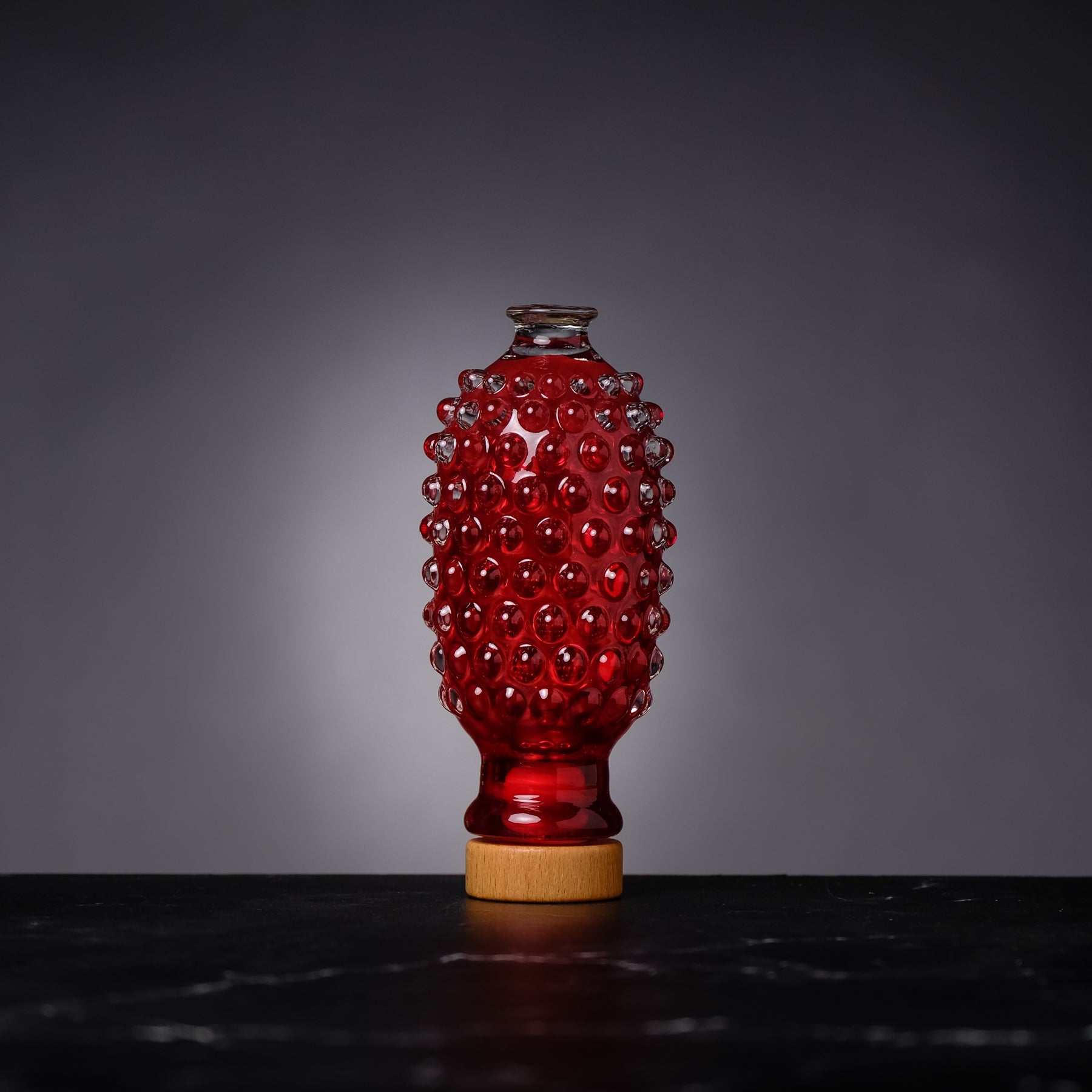 Red textured vase on a dark surface with a gray background
