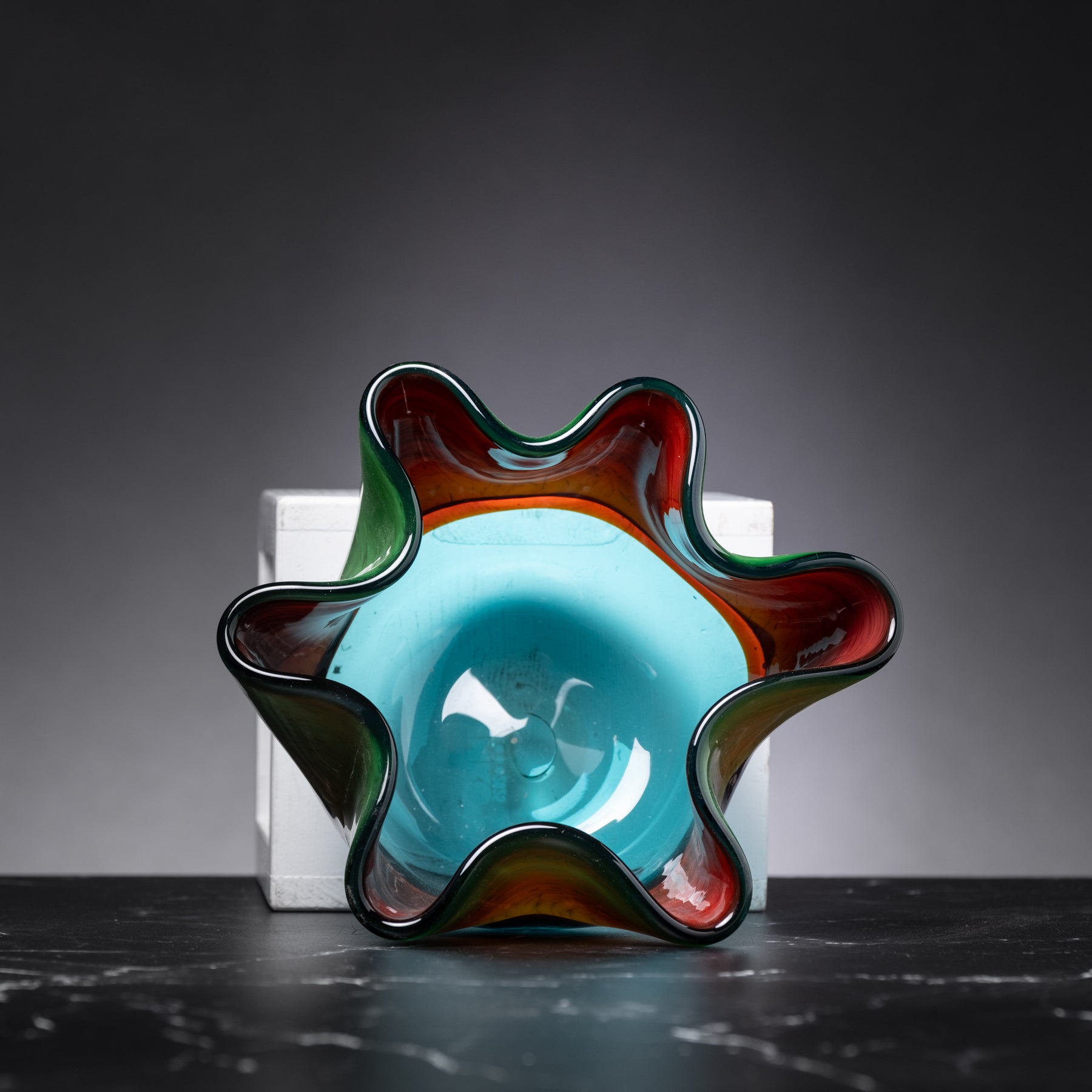 Colorful glass bowl with wavy design on a dark surface