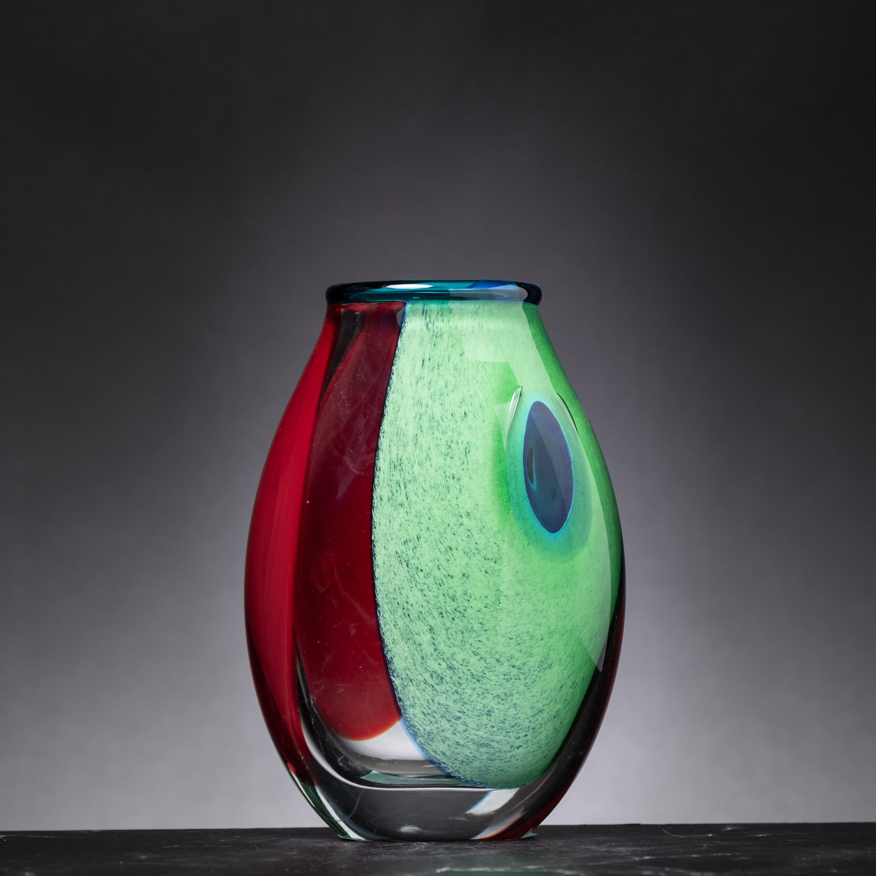 Colorful glass vase with red, green, and blue colors on a dark background