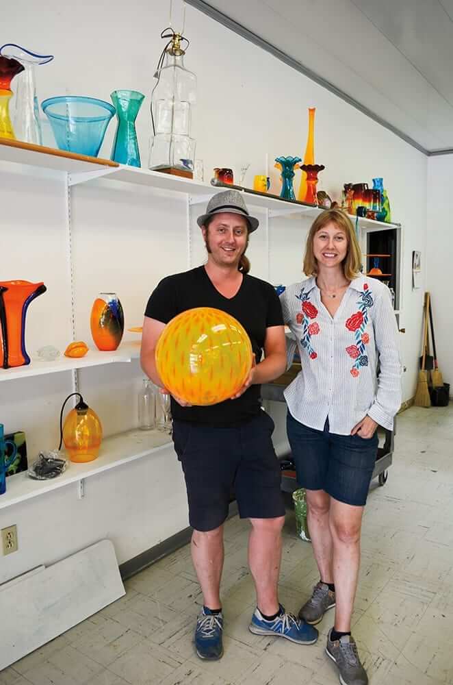 photo of Emm alters and Andrew Schaeffer in design studio hold a large glass ball.