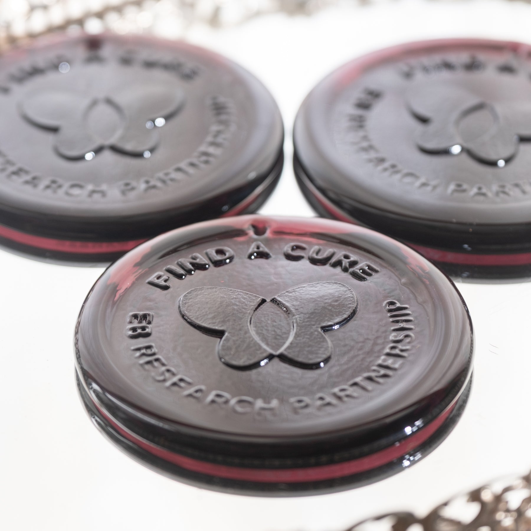 Three round black and red containers with a butterfly logo and text on a white background