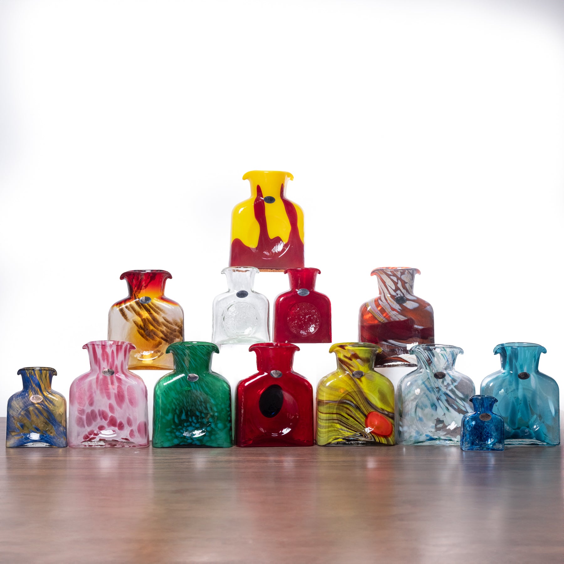 Collection of colorful glass vases on a wooden surface with a white background
