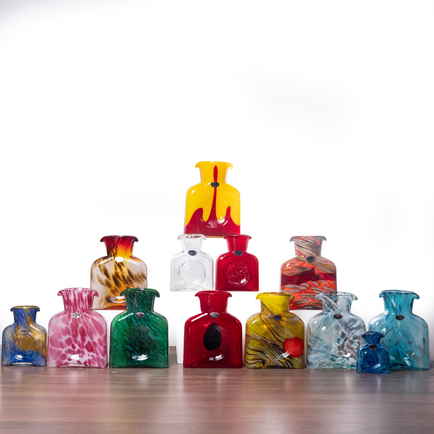 Collection of colorful glass vases on a wooden surface with a white background