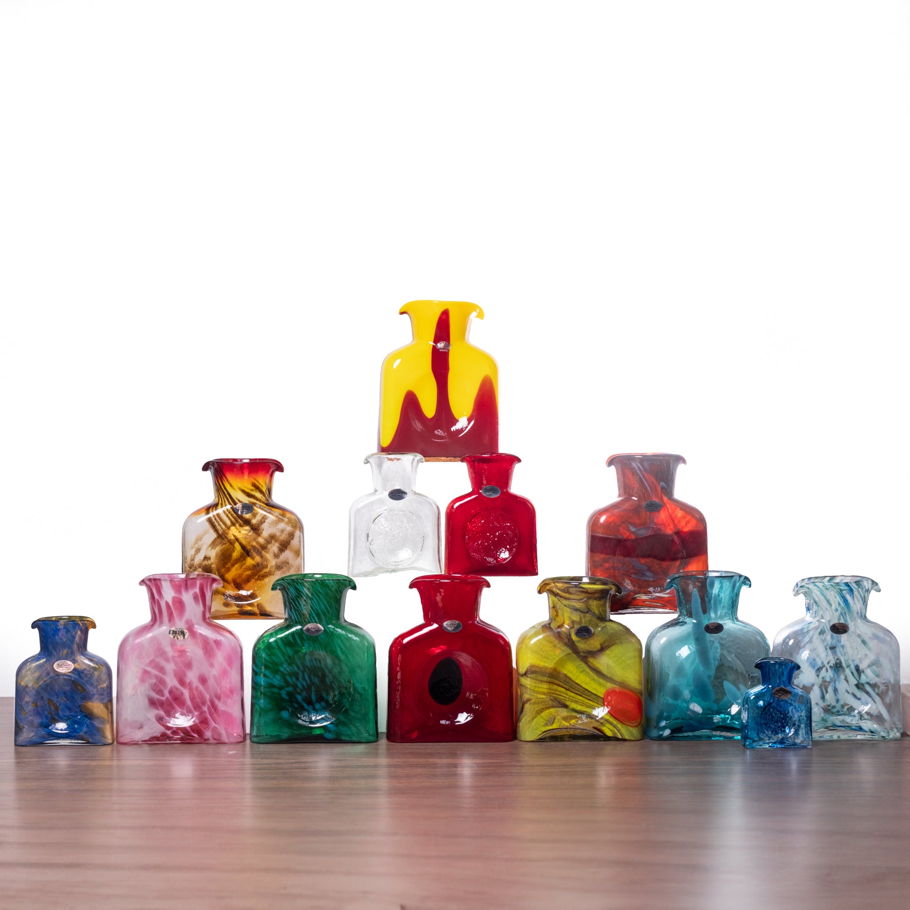 Collection of colorful glass vases on a wooden surface with a white background